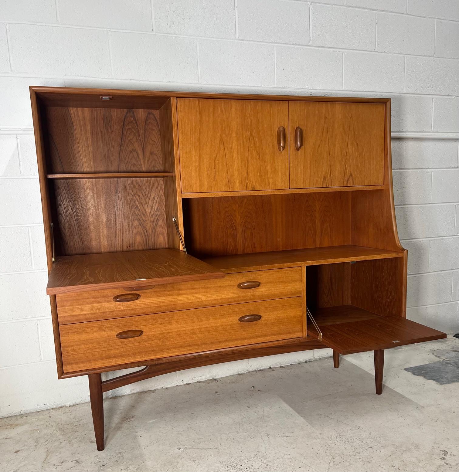 Mid century modern versatile teak highboard by G Plan. Featuring an upper large drop down cabinet that can be used as a small desk and lower drop down cabinet or bar.
Condition: Very good vintage condition. Minor signs of wear. Someone drilled a