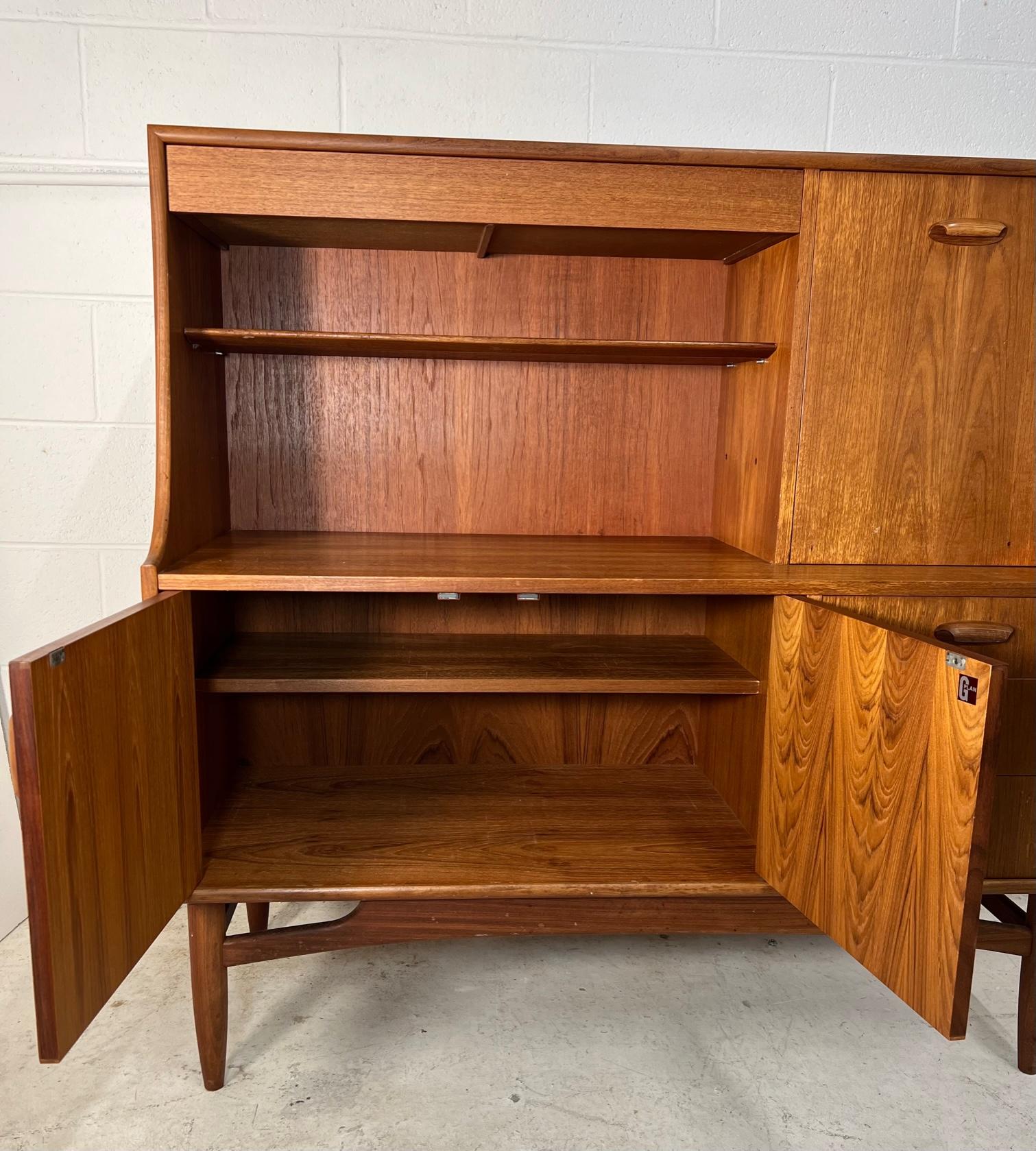 Mid century modern versatile teak highboard or server by G Plan. Featuring a drop down cabinet that can be used as a small desk and a drawer for silver ware at the top.
Three drawers and a cabinet with removable shelf at the bottom.

Condition: Has