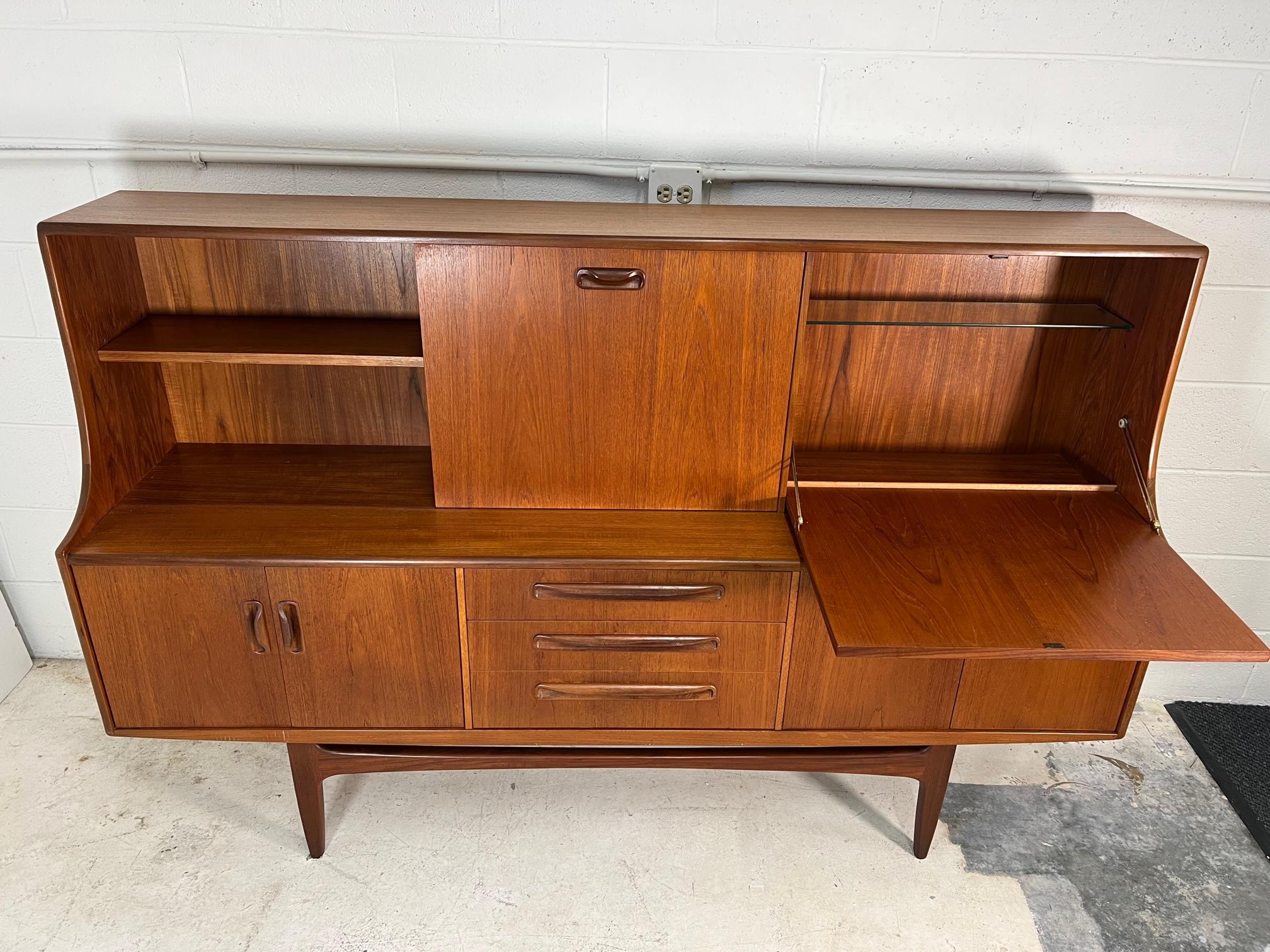 Mid-Century Modern versatile high board by G Plan. Featuring a sliding door and a small drop down desk that can comfortably hold a laptop or be used as a wine bar. Shelves are adjustable. Unfinished back.

Excellent condition. Very minor marks and