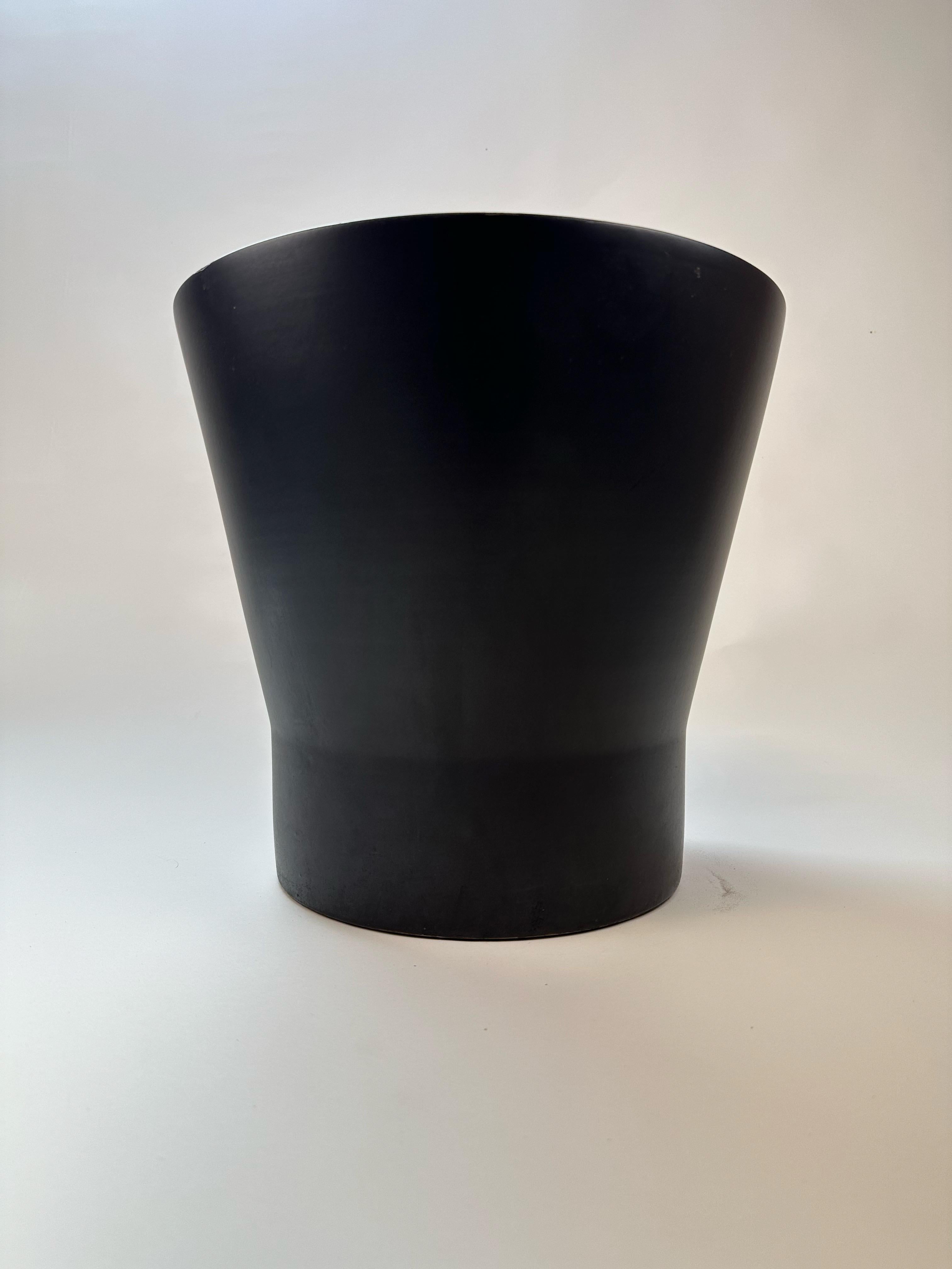 A striking example of timeless California design, this mid-century Gainey Ceramics planter features a clean, sculptural silhouette with a refined matte black finish. Its subtly flared, tapered form offers bold simplicity—making it a versatile piece
