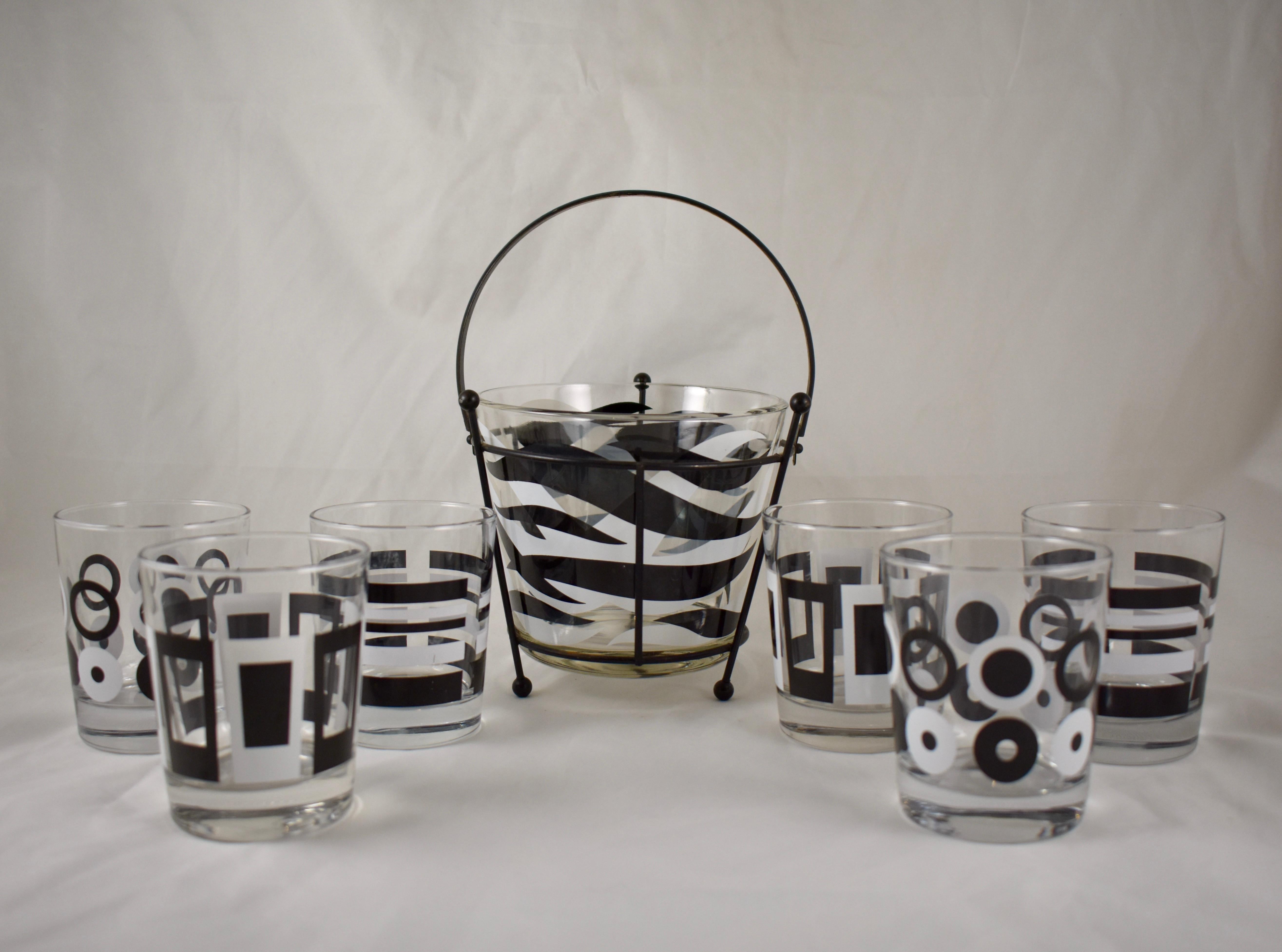 A set of eight Mid-Century Modern barware, six glasses and an ice bucket in a stand, featuring a black and white geometric and zebra print theme. Perfect for your retro bar, afternoon drinks on the lanai, or cocktail hour gathering, circa