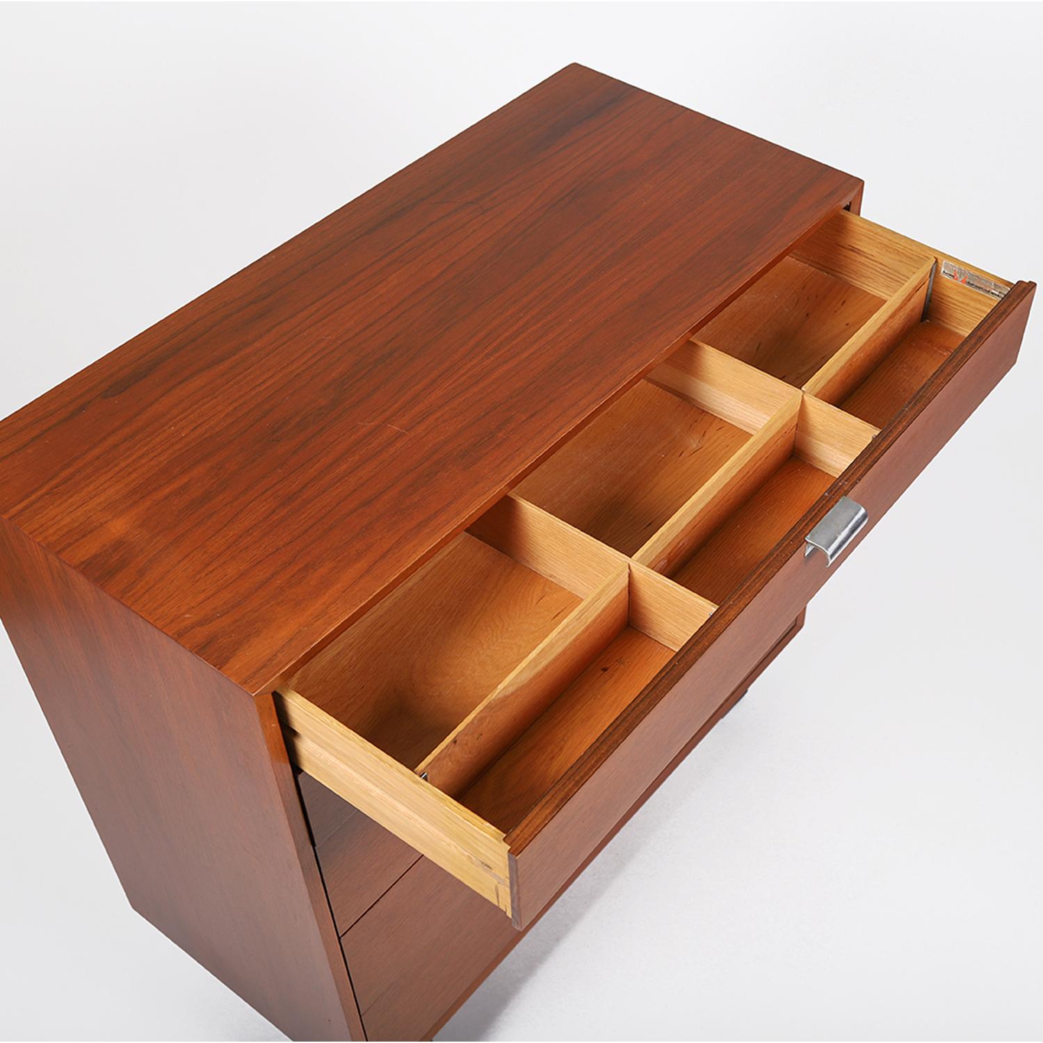 A classic mid-20th century drawer chest designed by George Nelson for Herman Miller. Warm lacquered walnut, top drawer divider, aluminum finger pulls and lacquered black angular base. Top two drawer faces are 5