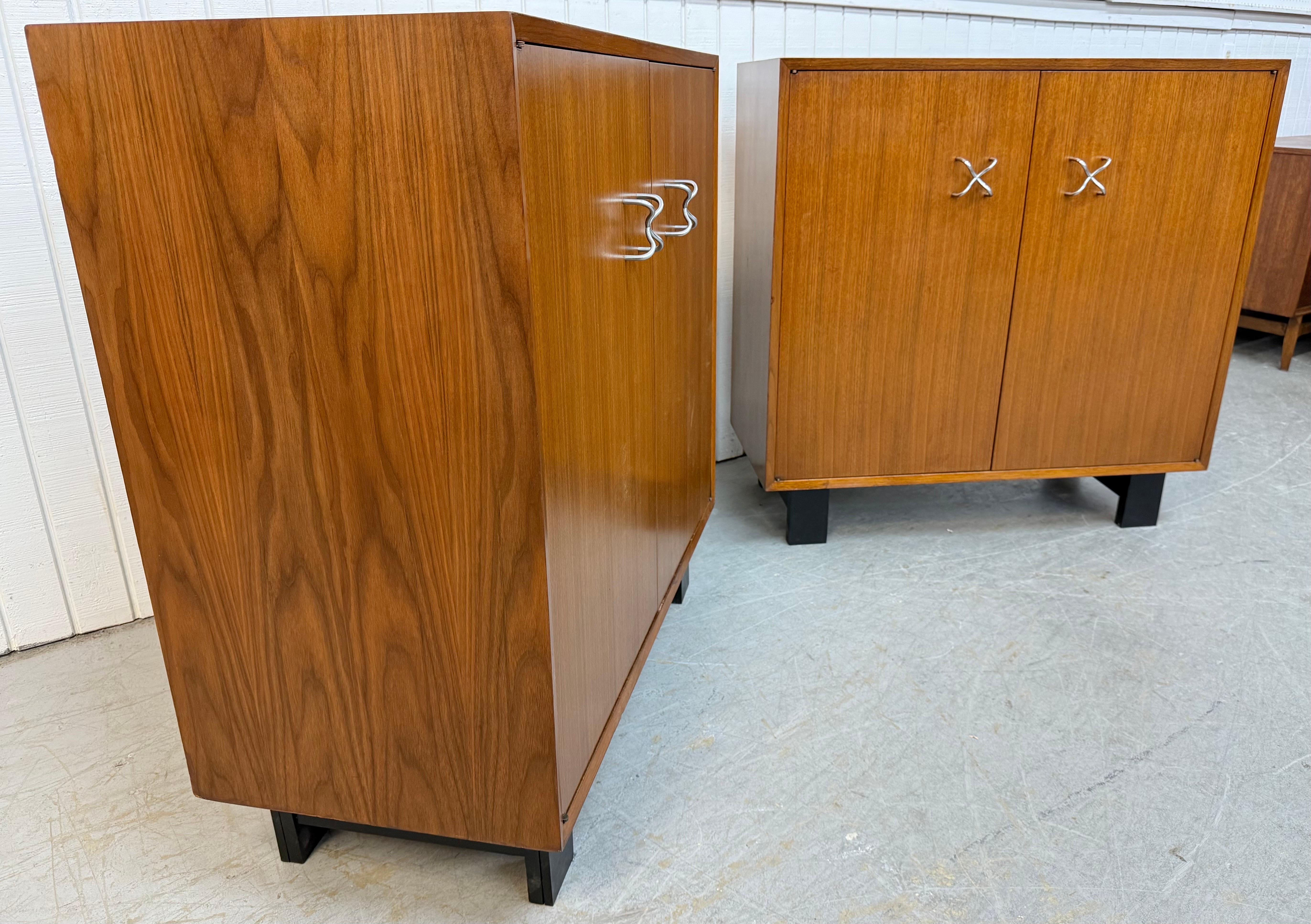 Questo annuncio si riferisce a una coppia di armadietti in noce di George Nelson per Herman Miller, risalenti alla metà del secolo scorso. Il design è lineare, le due ante si aprono per creare spazio, le gambe nere e moderne, la ferramenta originale