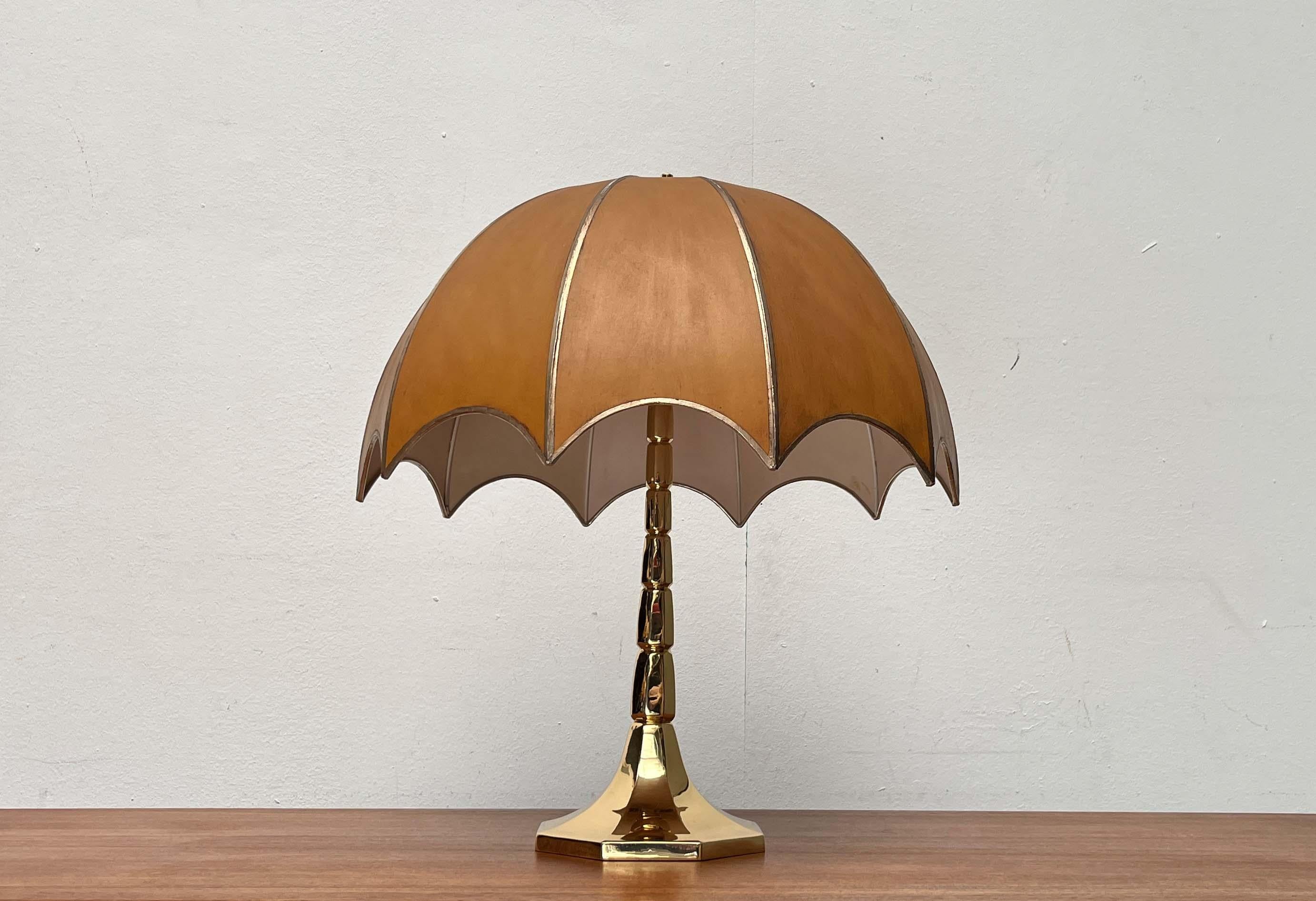 Impresionante lámpara de mesa del renombrado fabricante Goldkant.

La lámpara impresiona por su diseño ornamental y sus materiales de alta calidad. La base segmentada y la forma de la sombrilla recuerdan a una palmera. La pesada base es de latón. La