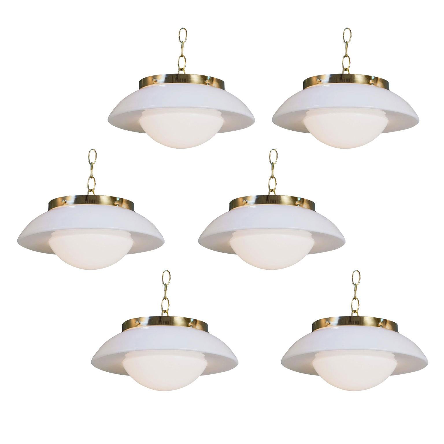 Five German milk glass pendants: interesting, mid-century modern milk glass shades as pendants finished with brass hardware. Fabricated circa 1950s in Germany. Newly wired for use within the US with all UL approved parts. Single porcelain Edison