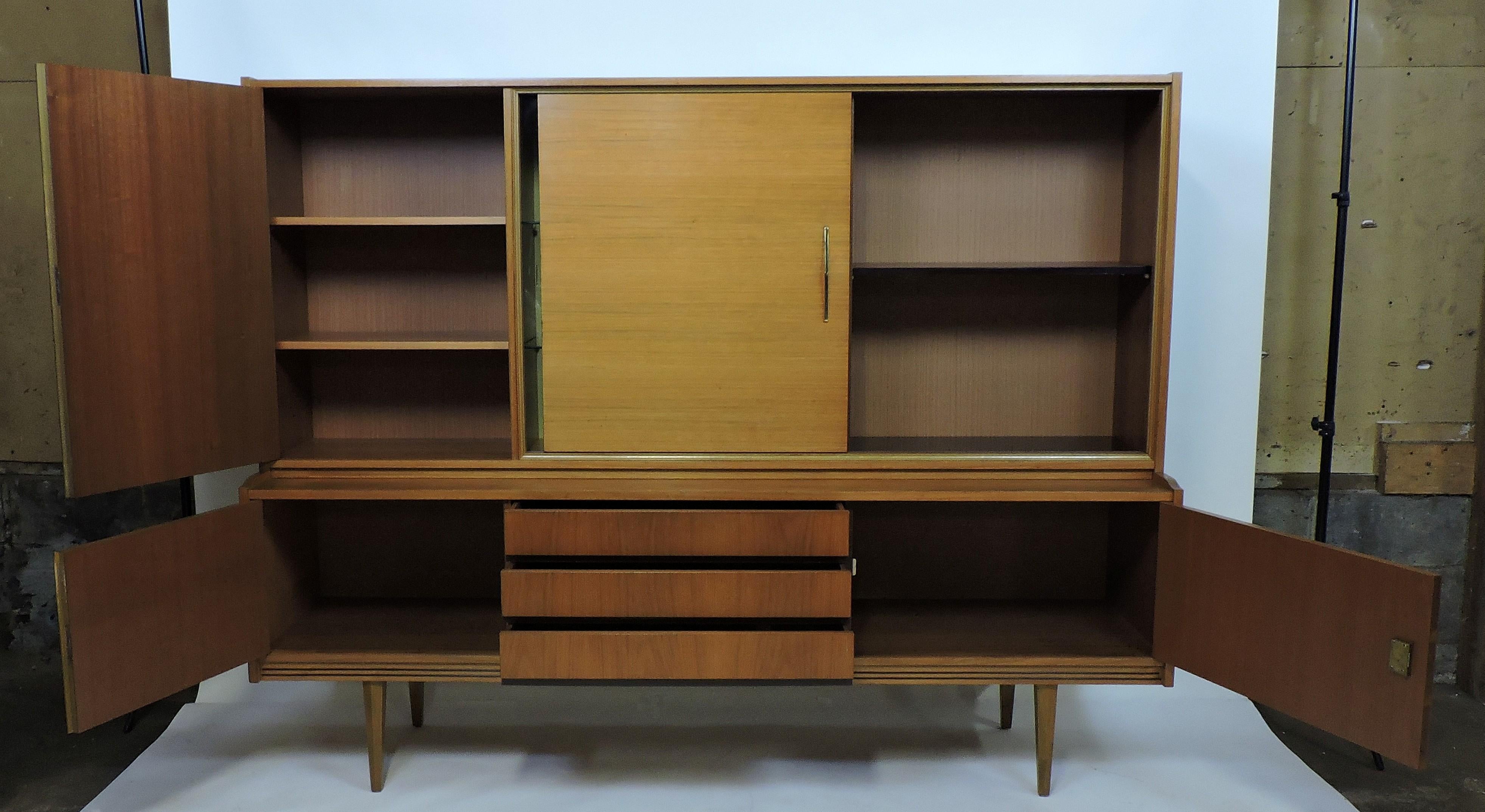 Handsome and well made midcentury teak cabinet made in Germany by Munker Modell. This piece has lots of storage space with three drawers, three locking compartments, a compartment with a sliding wood door, and a compartment with a sliding glass