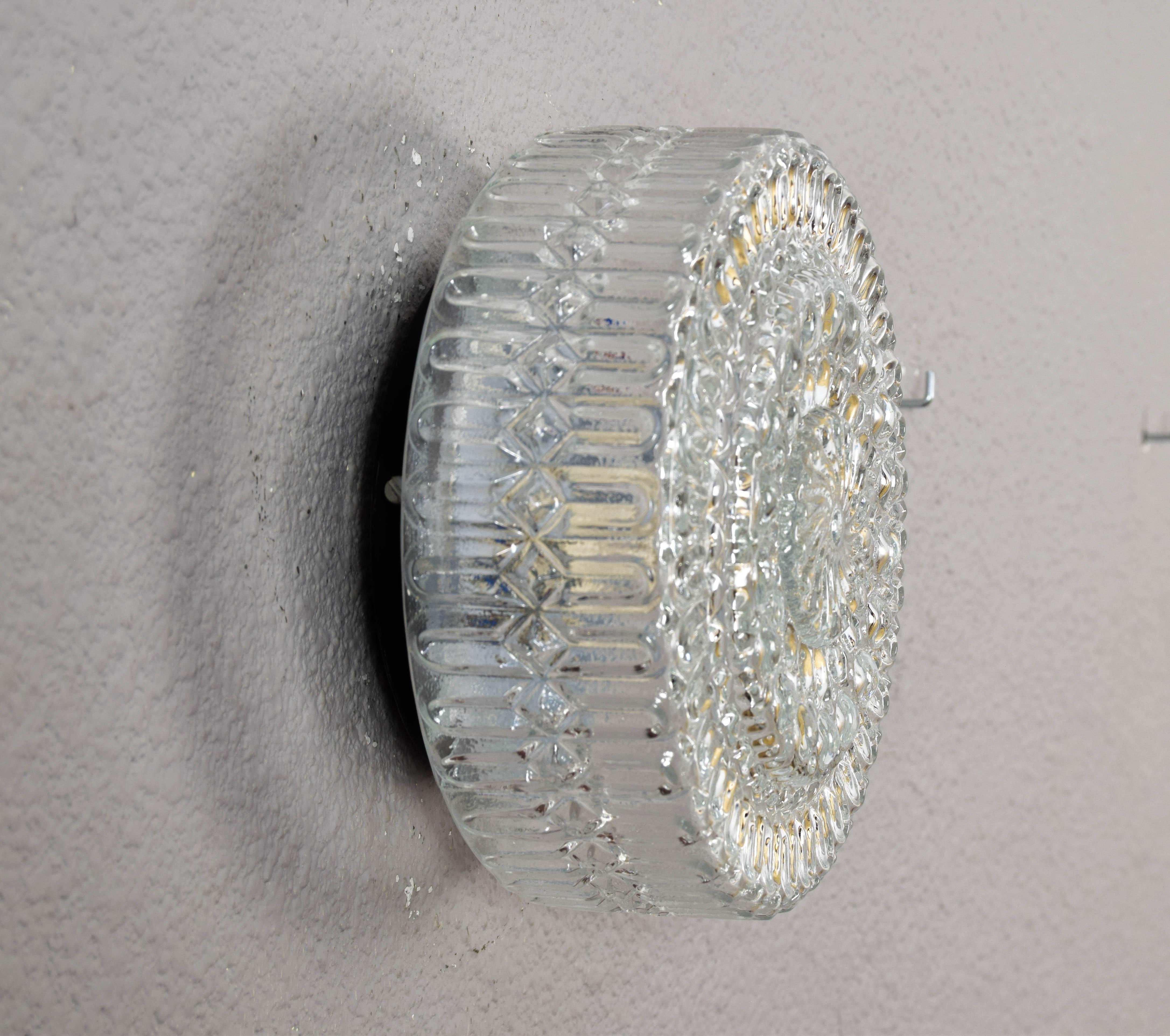 Beautiful wall light or flush mount lamps of Germany origin manufactured in the 1960s.
Circular in shape and made of transparent cut glass, they consist of an E27 light bulb socket.
The shapes of the glass create a very pleasant effect of light