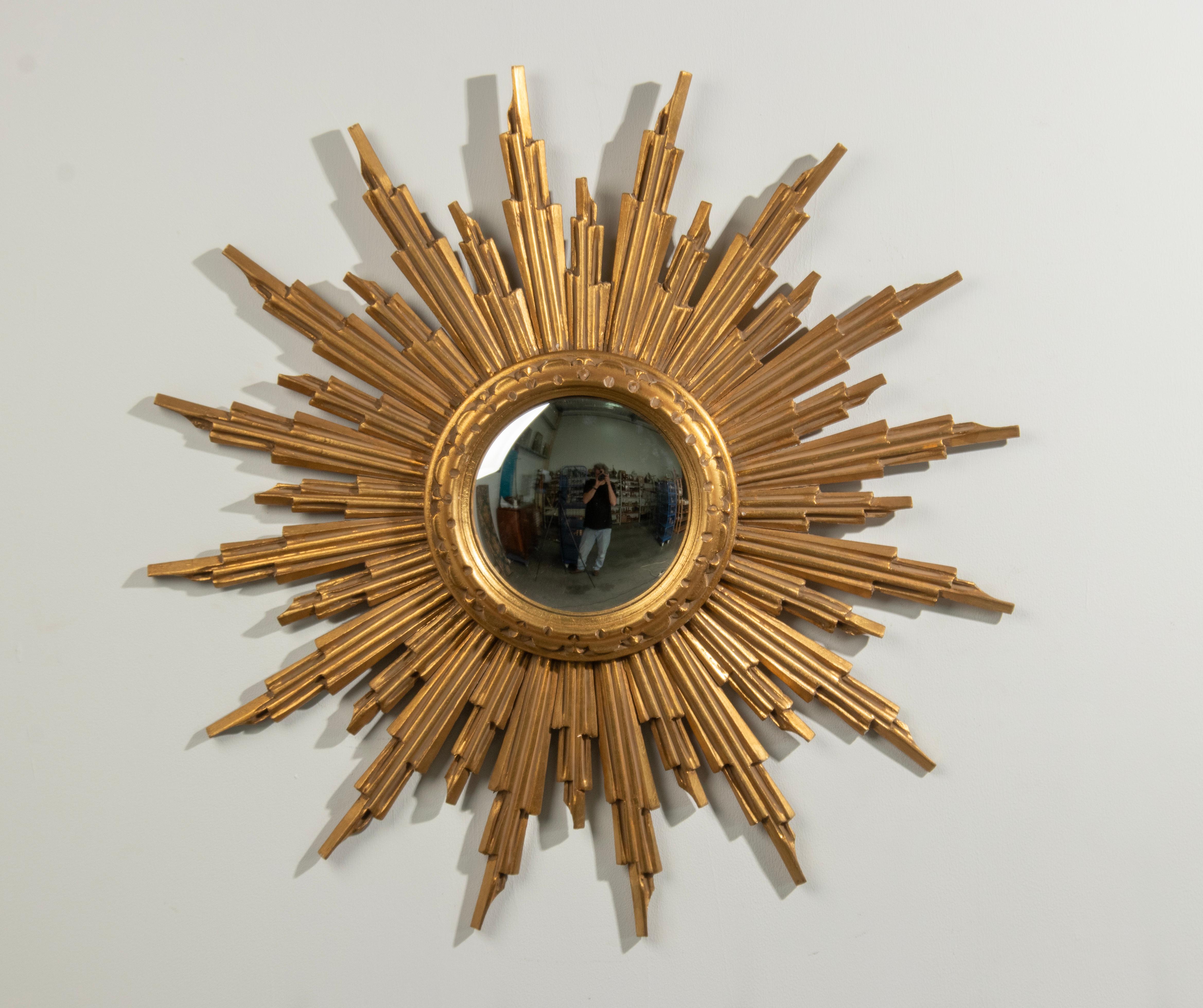 Magnifique miroir convexe en bois doré avec rayons multiples sculptés à la main. Le cadre est en bois, magnifiquement sculpté à la main. Avec miroir en verre convexe. 
 Datant d'environ 1950, fabriqué par A.I.C. Belgium, Bruxelles. Le Label original