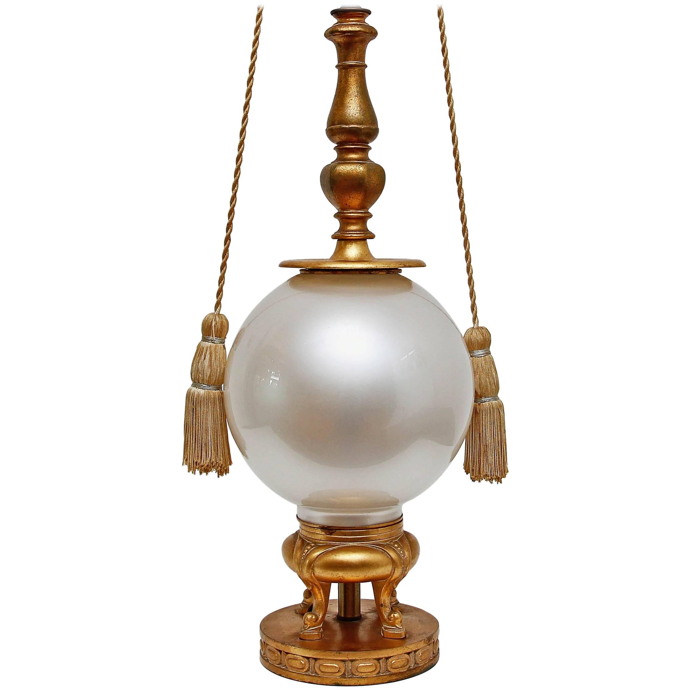 Vintage Hollywood Regency lamp by Marbro. Opaline glass globe base with gold gilt metal mounts. Original silk tassel pulls. No shade.