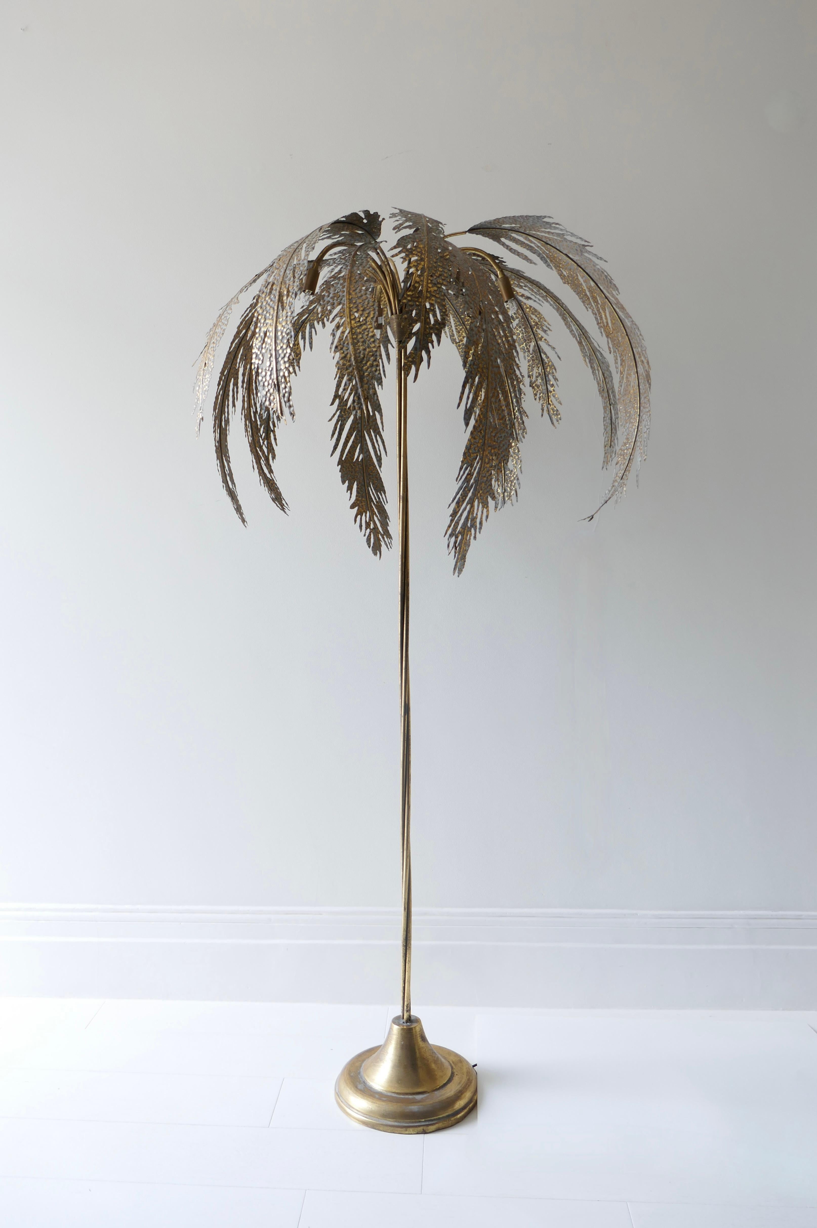A highly decorative floor lamp in the shape of a Palm tree. The leaves' circumference is 80cm whilst the lamp base is 30cm. 3 bulbs are hidden under the leaves. Each leaf is removable and reposition-able 
The lamp is in gilded metal to underline