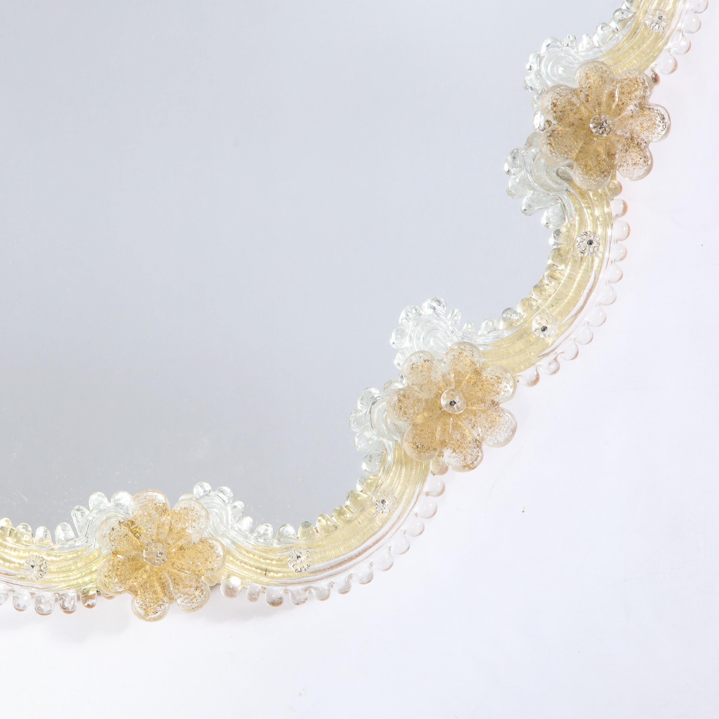This elegant Mid-Century Modern mirror was realized in Italy circa 1960. It features a scalloped Silhouette consisting of a sculptural channeled handblown Murano border adorned with florettes with 24kt gold flecks. The frame that peaks out subtly