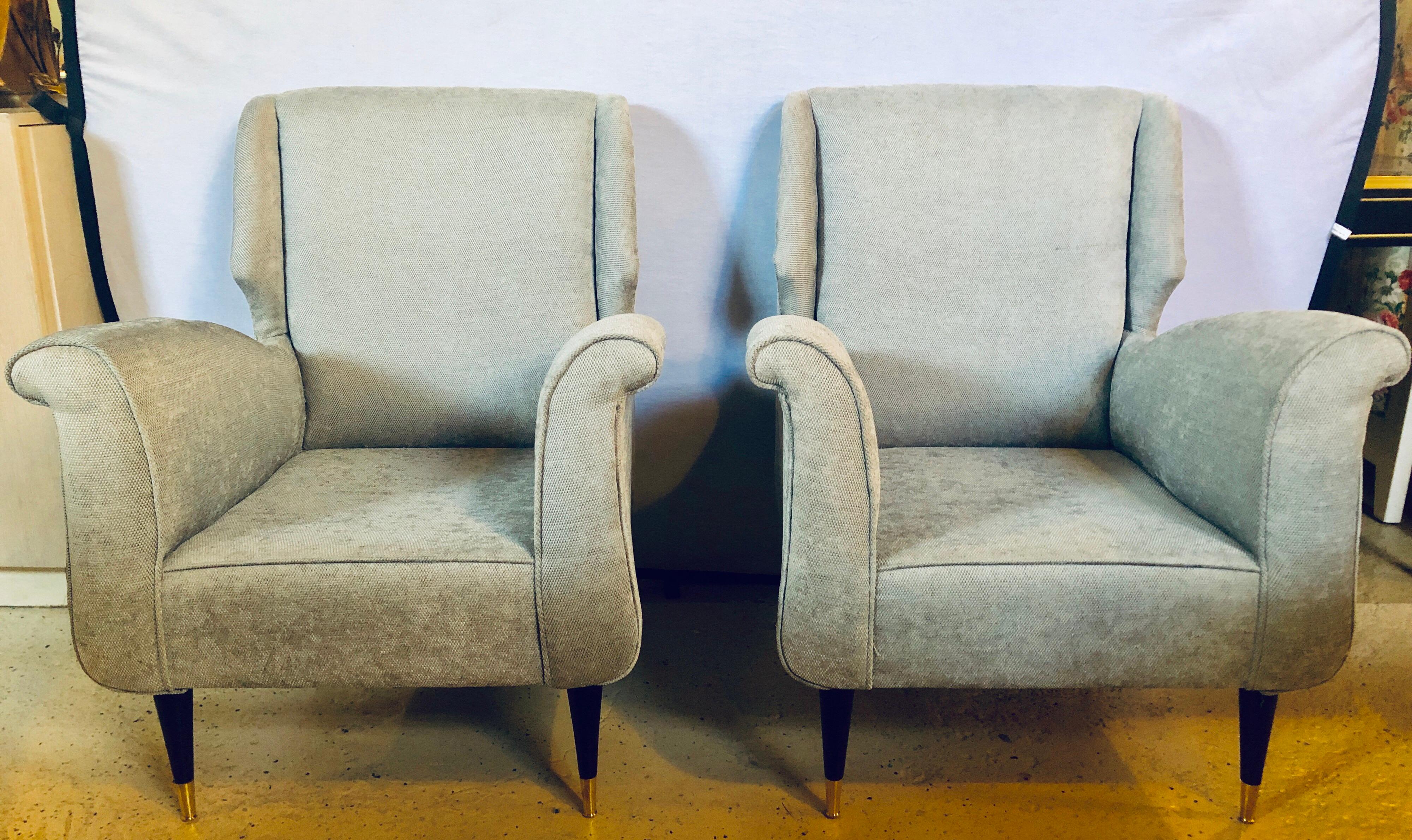 Pair of Mid-Century Modern Gio Ponti style arm or wing back chairs. These finely detailed sleek and stylish armchairs depict this iconic designer’s style for flair and simplicity at his highest level. The tapering mahogany legs sitting on brass