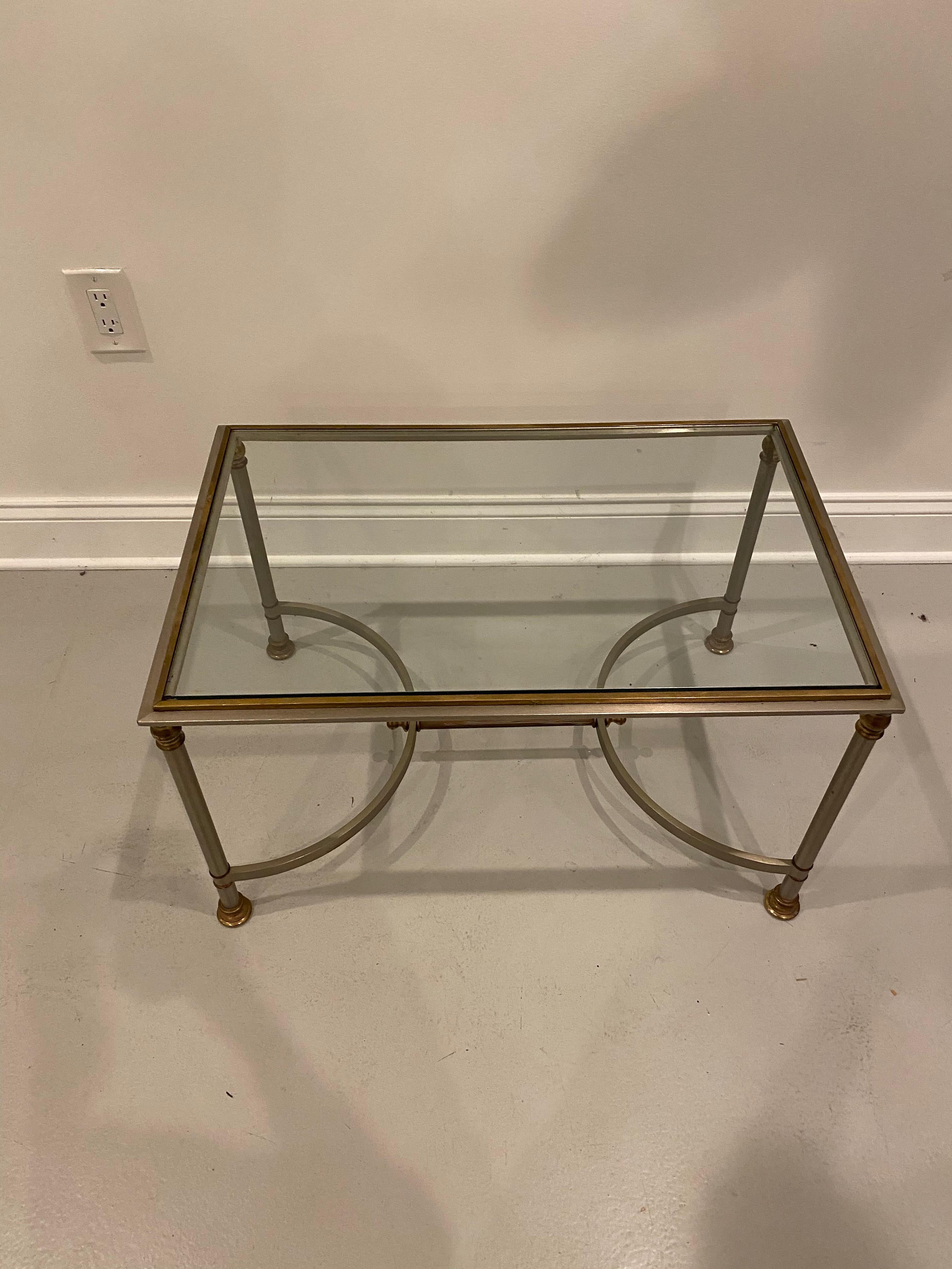 Mid-Century Modern coffee table. The bass is brass with a glass top.