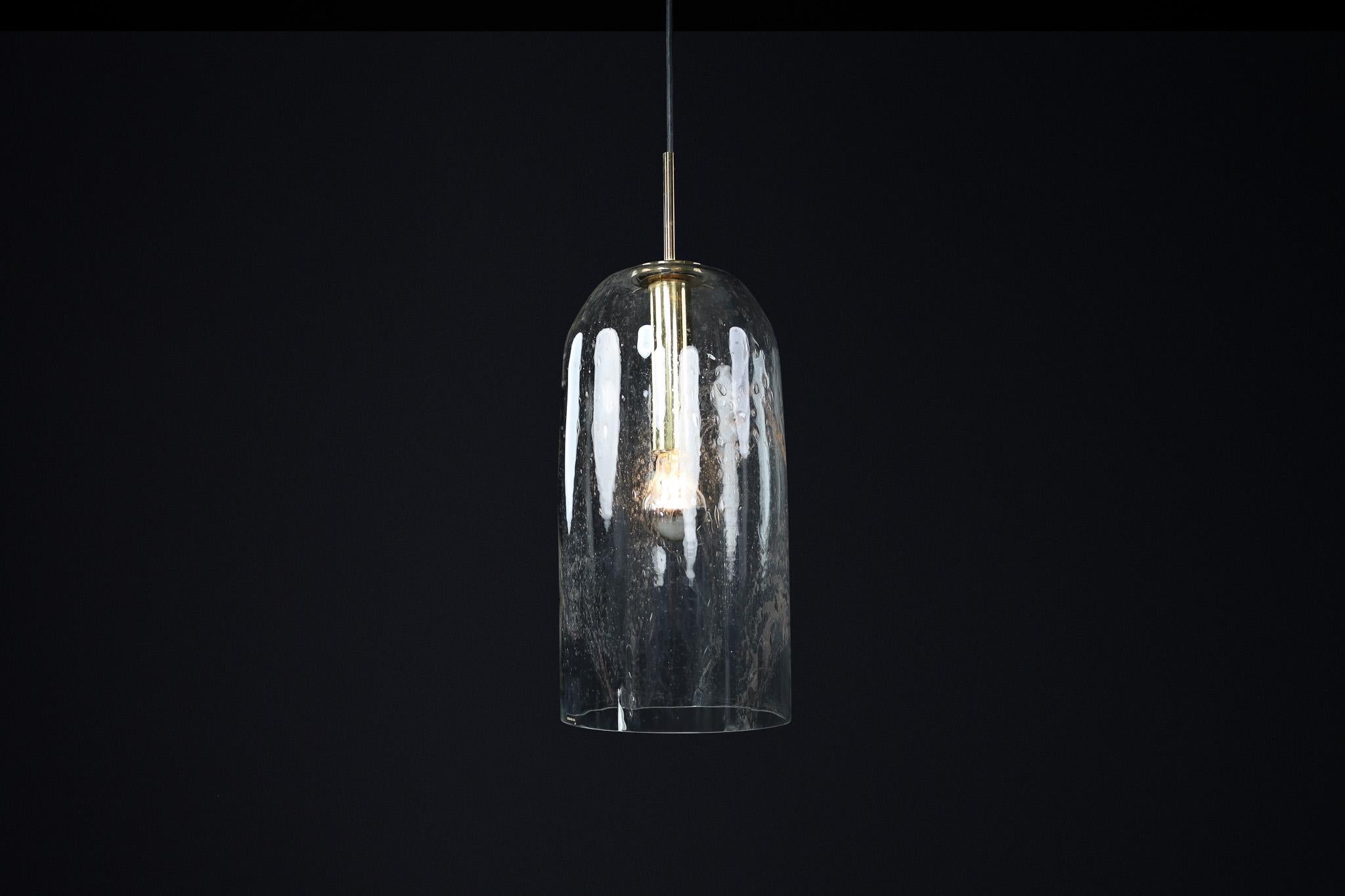 Mid-Century Modern Glass and Brass Pendants by Doria Leuchten, Germany 1970s

These pendants by Doria Leuchten of Germany showcase a sleek cylindrical glass shade with a gently domed top, allowing light to shine beautifully. The transparent glass