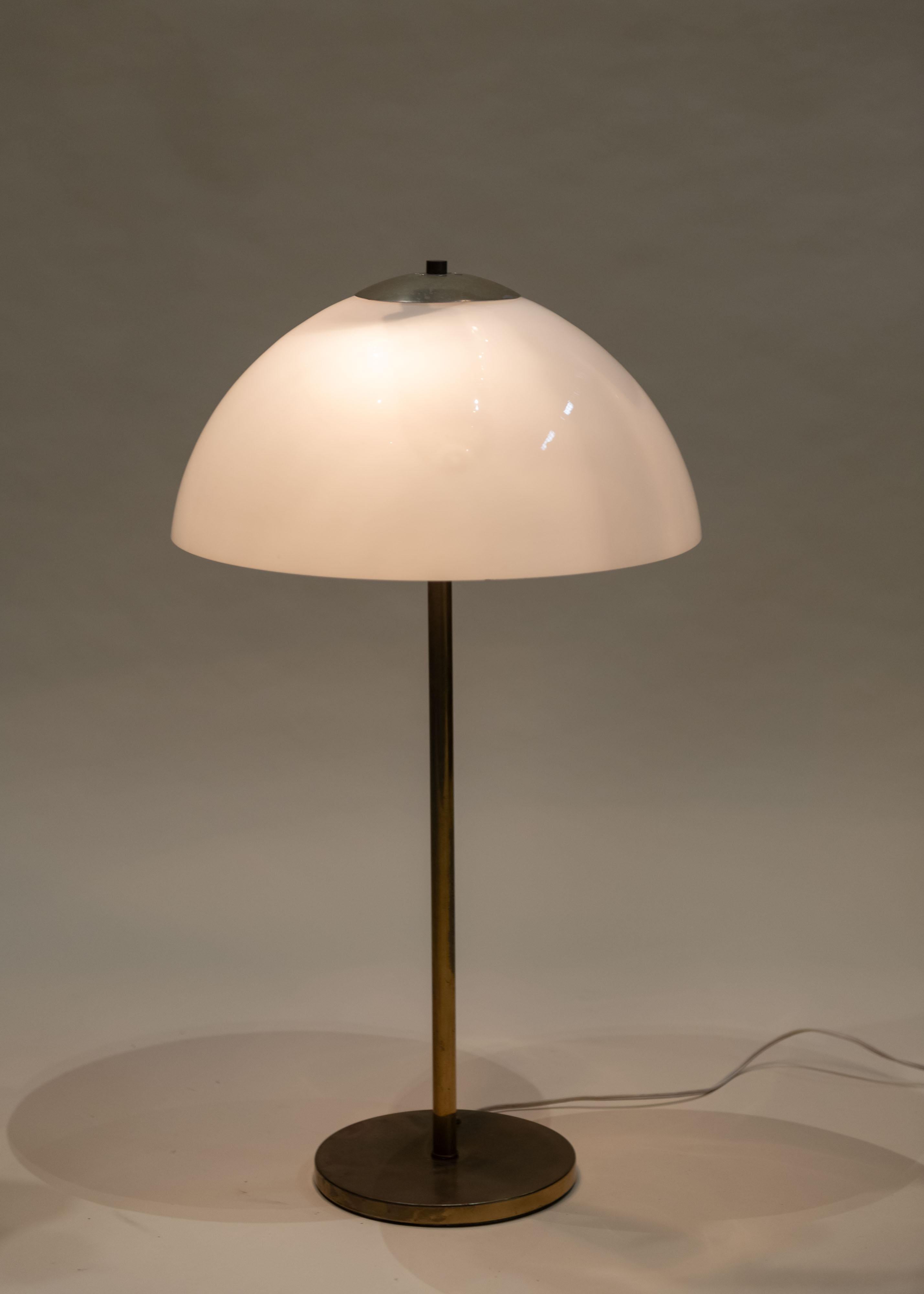 This Mid-Century Modern Italian table lamp features a domed white glass shade paired with a slender brass stem and circular base. Its clean lines and warm patina reflect the refined minimalism and elegance of 1960s Italian design.