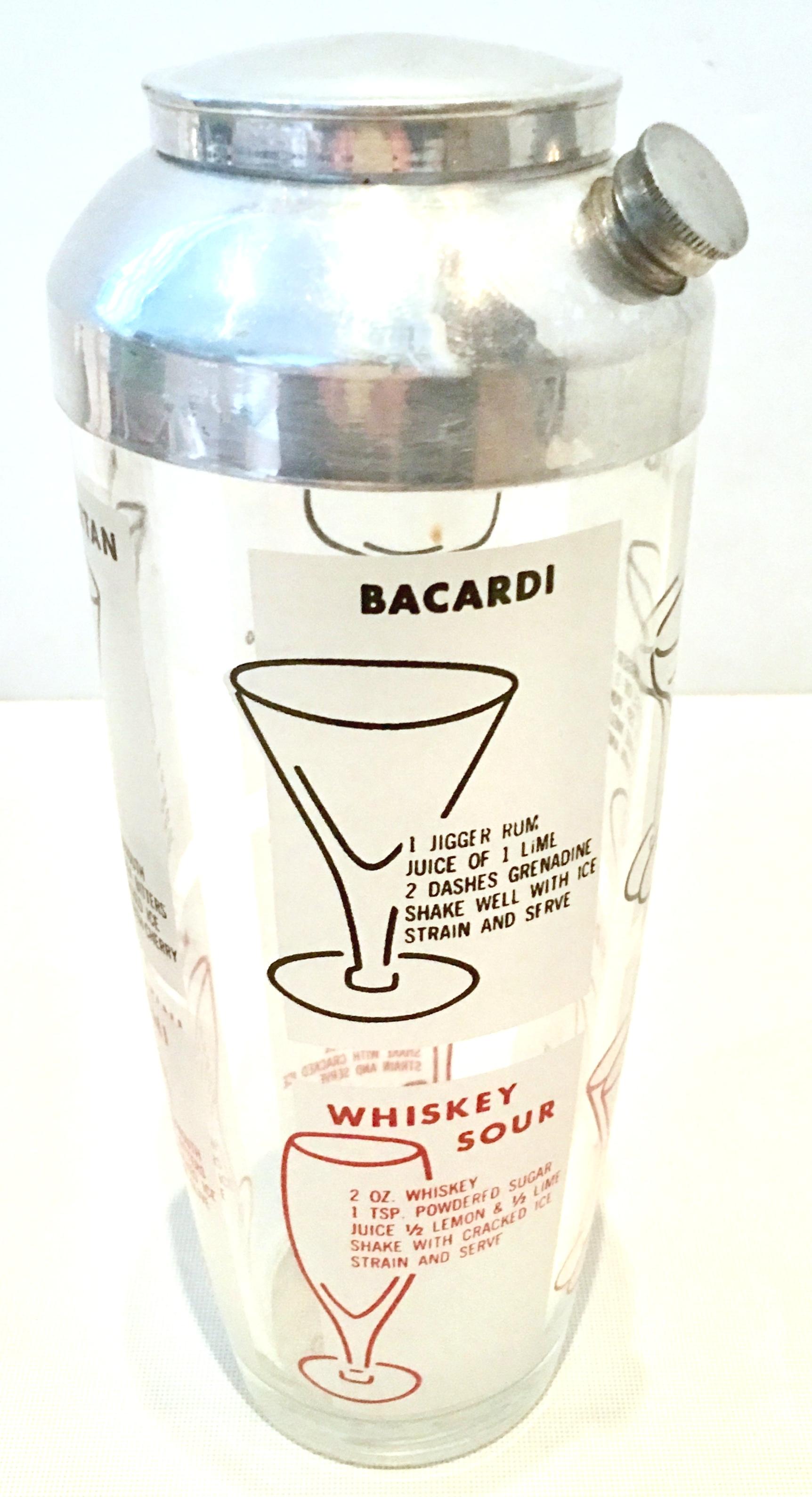 Mid-Century Modern glass and chrome printed drinks recipe cocktail shaker. Features a white, black and red font printed MCM era drinks recipe pattern and a screw top that allows drinks to be poured through a strainer.