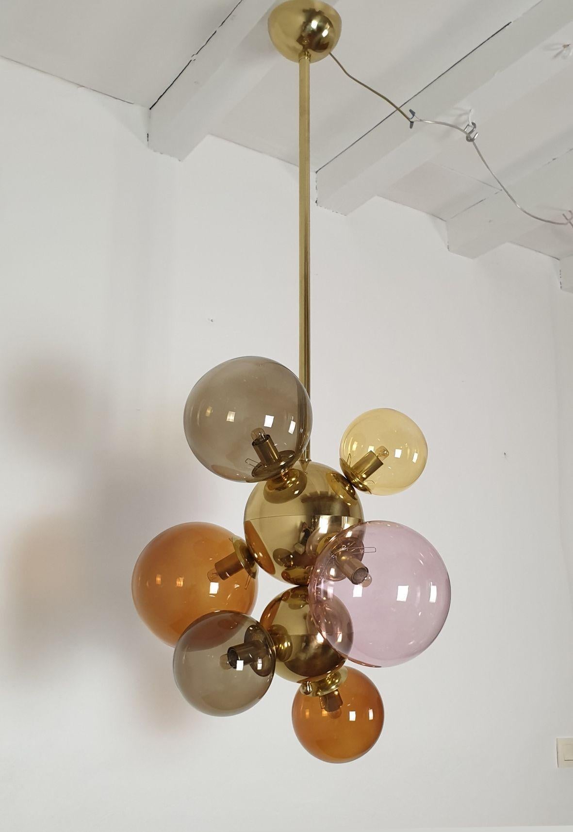 Tall Mid Century Modern glass balls and brass chandelier or pendant light, Italy circa 2000s.
The chandelier is made of different sizes glass balls and polished brass balls and stem.
The glass balls are in different pastel colors: lilac, amber, dark