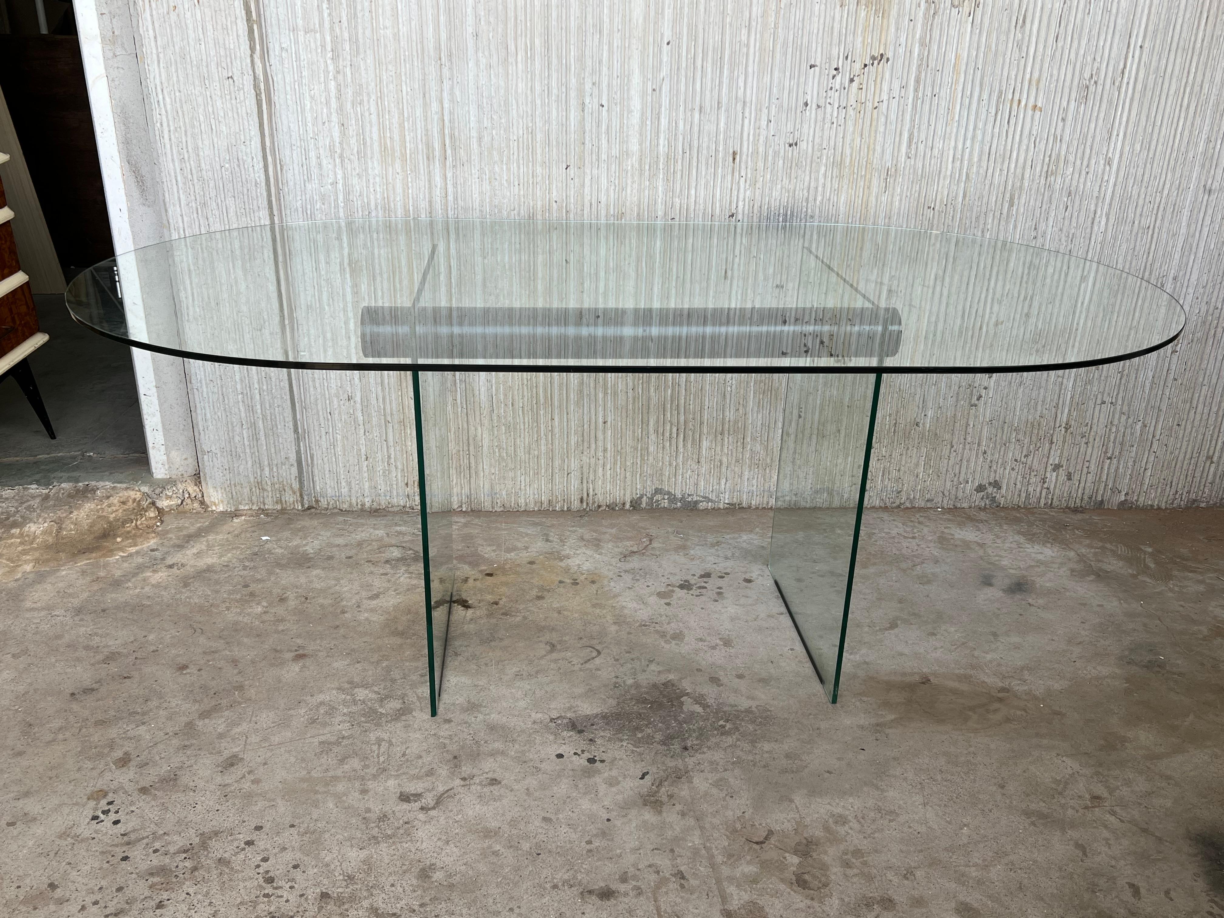 Mid-Century Modern glass dining room table with glass legs and metal cylinder like an stretcher.