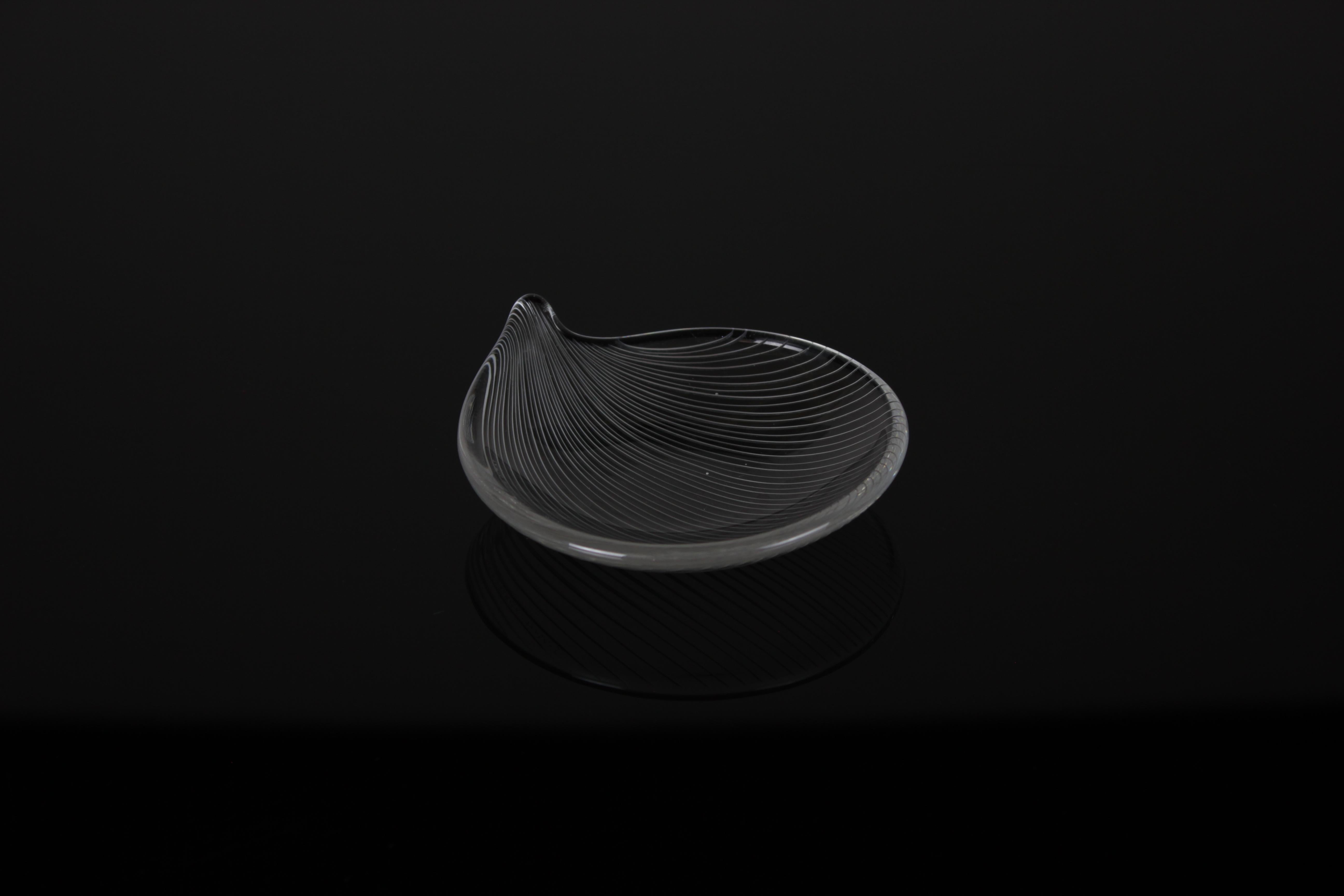 Immerse yourself in the timeless allure of mid-century modern design with this exquisite glass dish crafted by the legendary Tapio Wirkkala for Iittala. Shaped like a delicate leaf, this masterfully designed piece captures the essence of nature with
