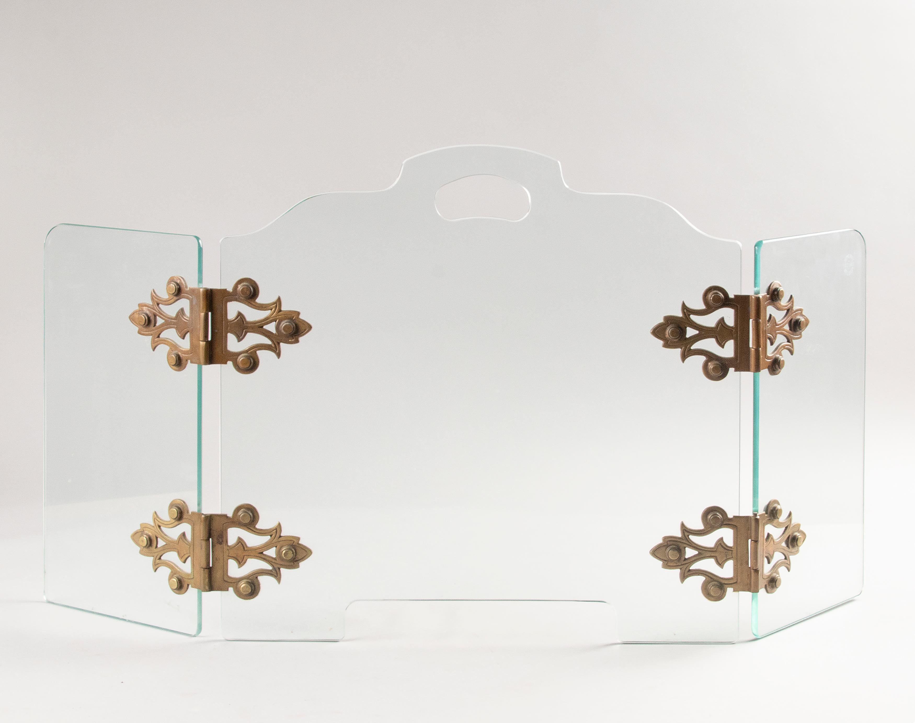 A mid-century fire screen consisting of three panels of glass with brass hinges. It has heat proof security glass, which can withstand the heat of the flames of the fire mantel. Glass made by 