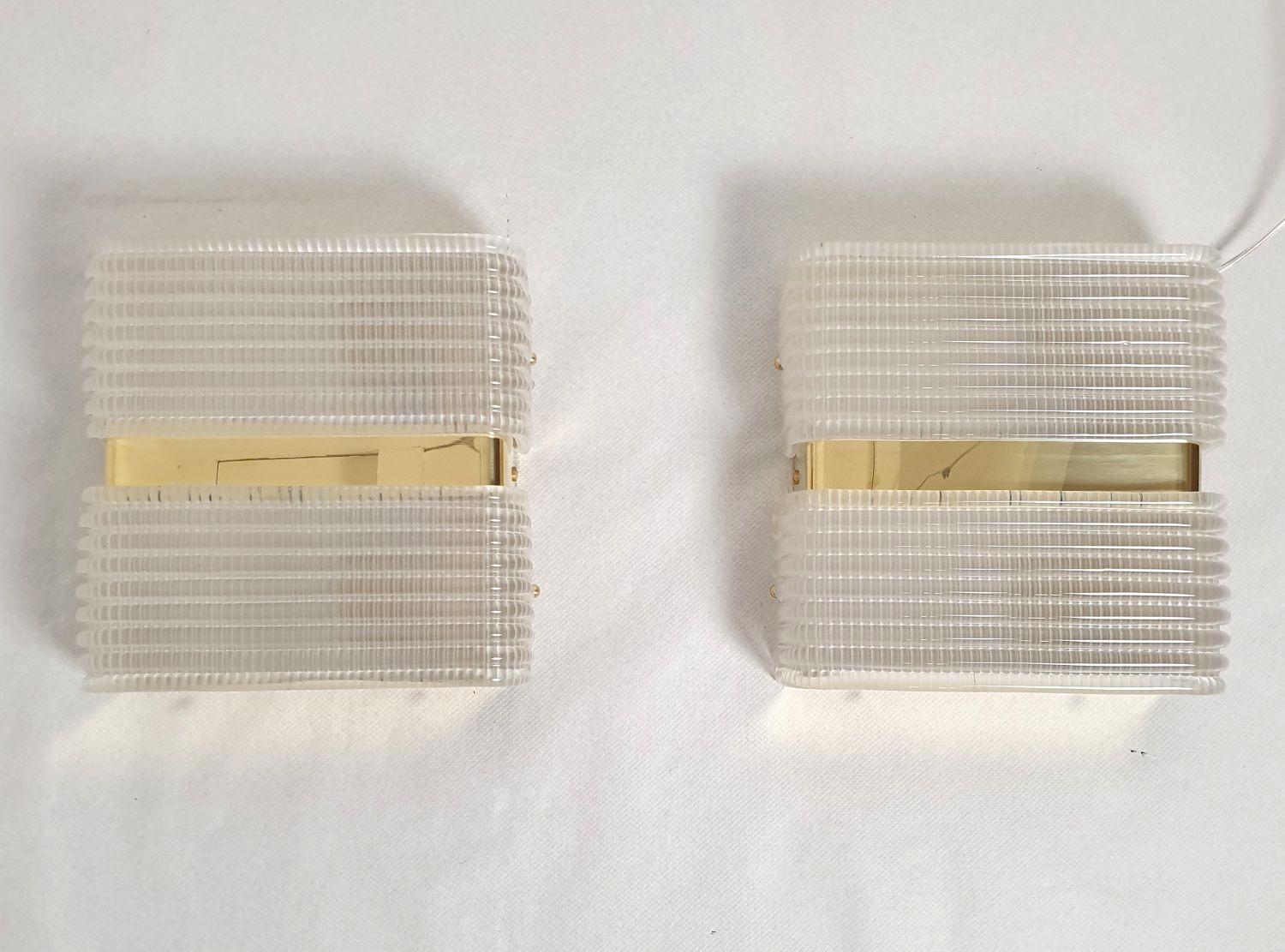 Pair of Mid Century Modern wall sconces, attributed to Sciolari, Italy 1970s.
The sconces are almost square; made of polished brass mounts and 2 textured clear Murano glasses.
The mid century modern sconces have a geometrical shape.
They have an Art