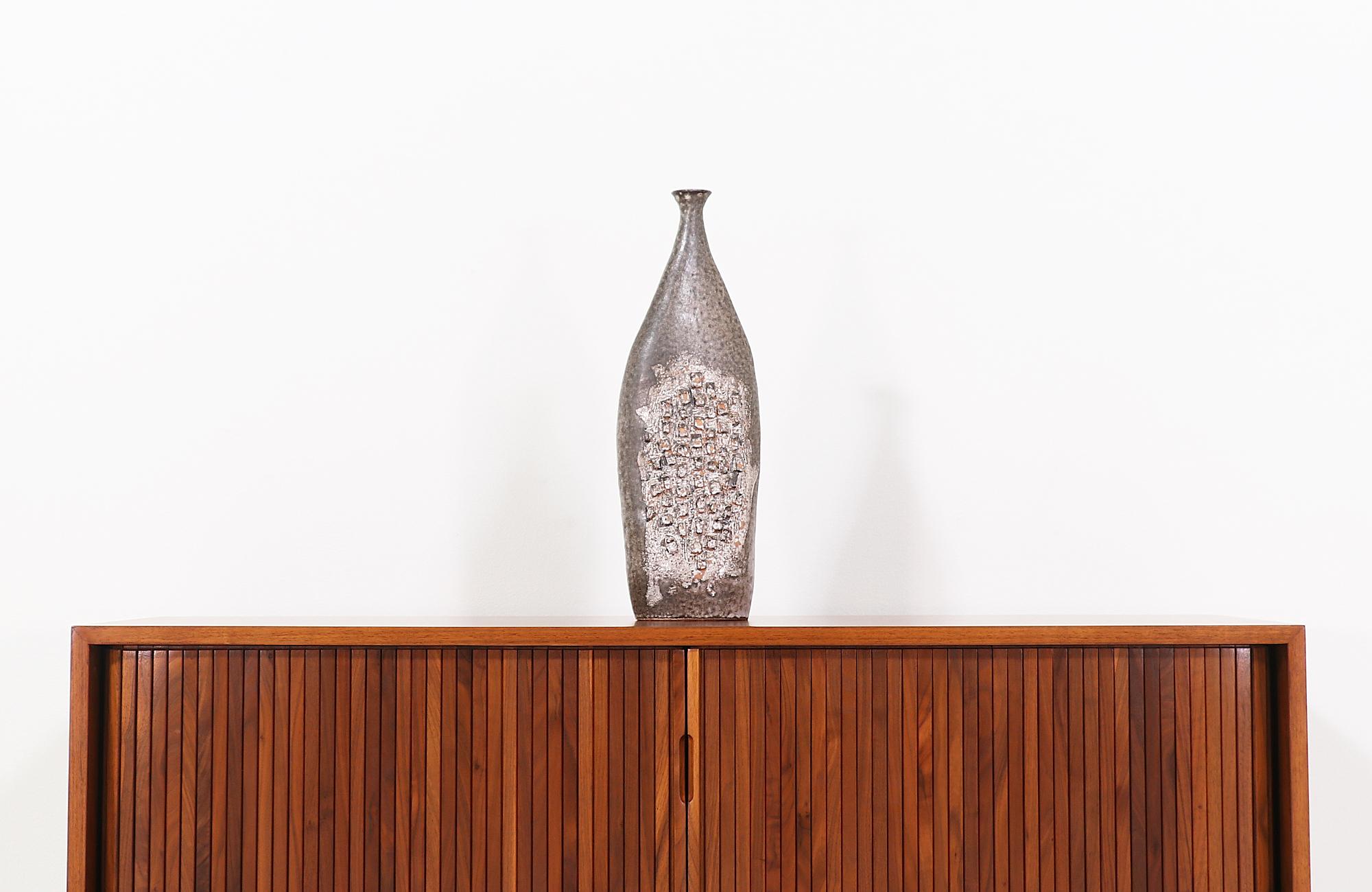 Unique Mid-Century Modern ceramic vase designed and manufactured in the United States in 1958. This biomorphic vase features a tall glazed ceramic body in earthy tones with a rich combination of textures and cubist detailing in the front and back.