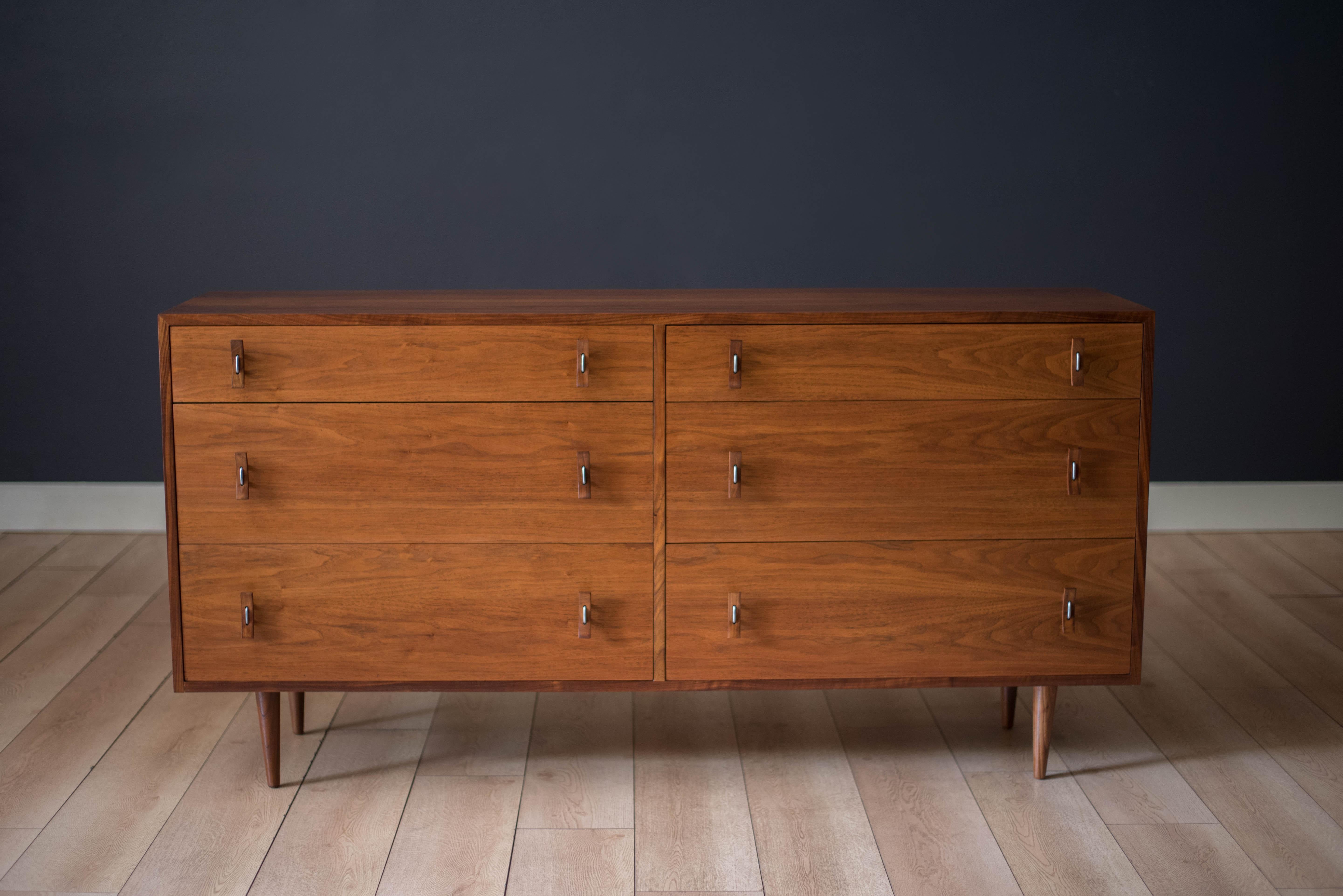 Vintage double dresser chest designed by Stanley Young for Glenn of California, circa 1950s. Features natural walnut variations in the grain pattern accessorized by floating bent metal and sculpted wood handles. Supported by classic midcentury dowel