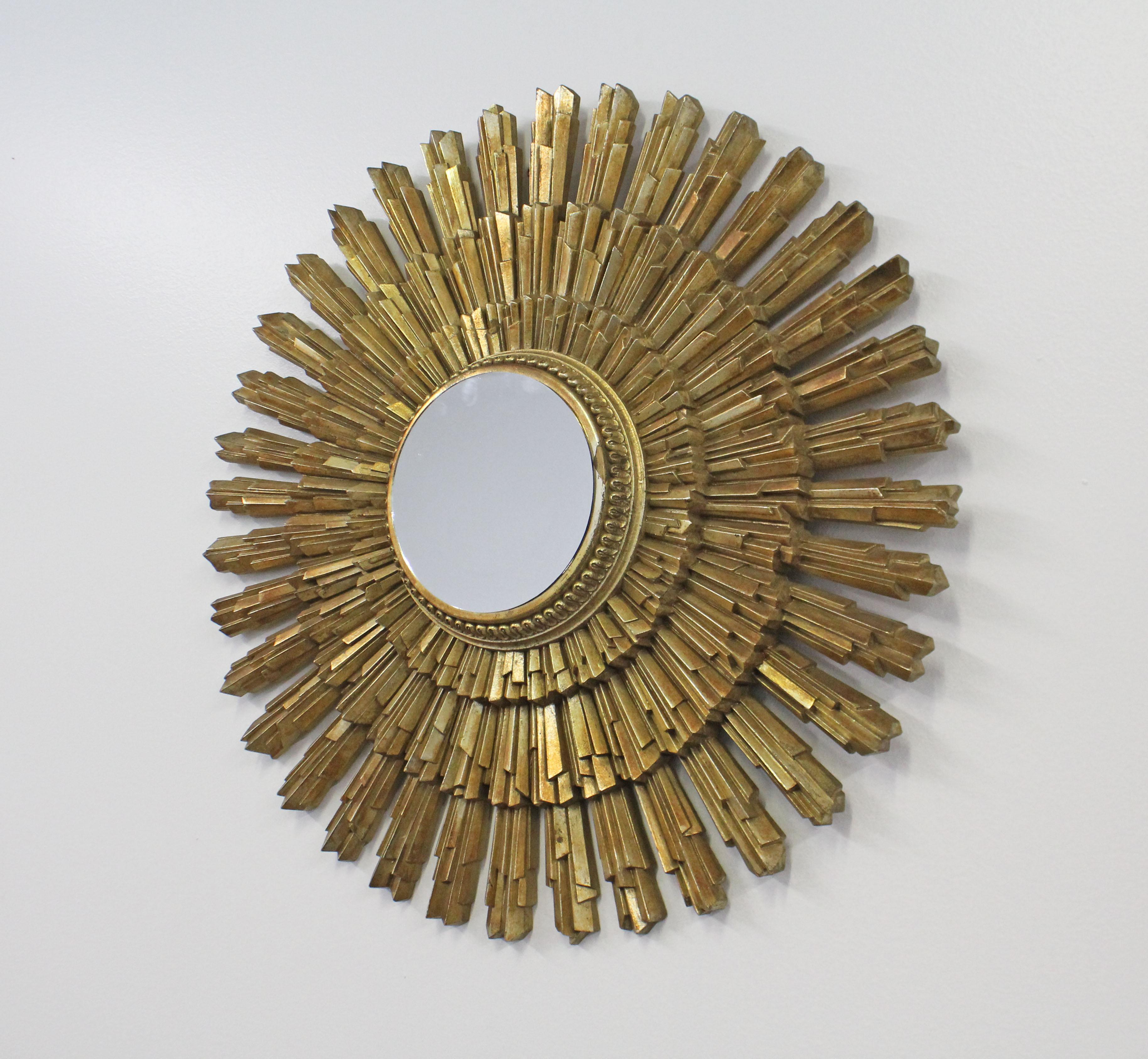 Offered is a super unique, vintage midcentury wall mirror in the shape of a starburst. Features a gold gilded enamel frame and center mirror. It is in good condition with minor flaws and wear around the frame (see photos). It has a small loop for