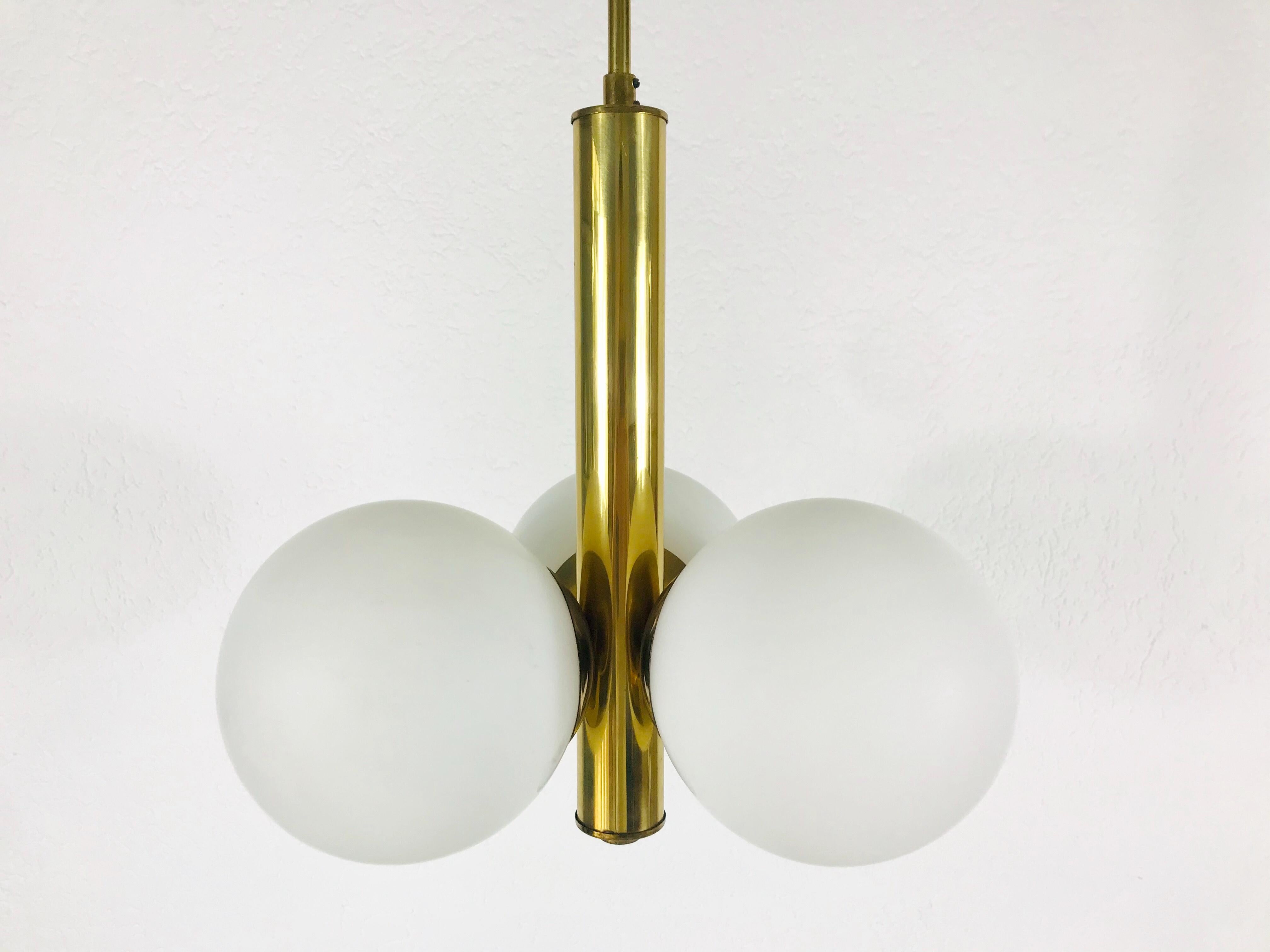 A midcentury Kaiser chandelier made in Germany in the 1960s. It is fascinating with its Space Age design and three opaline glass balls. The body of the light is made of polished brass, including the arms. 

The light requires three E14 light bulbs.