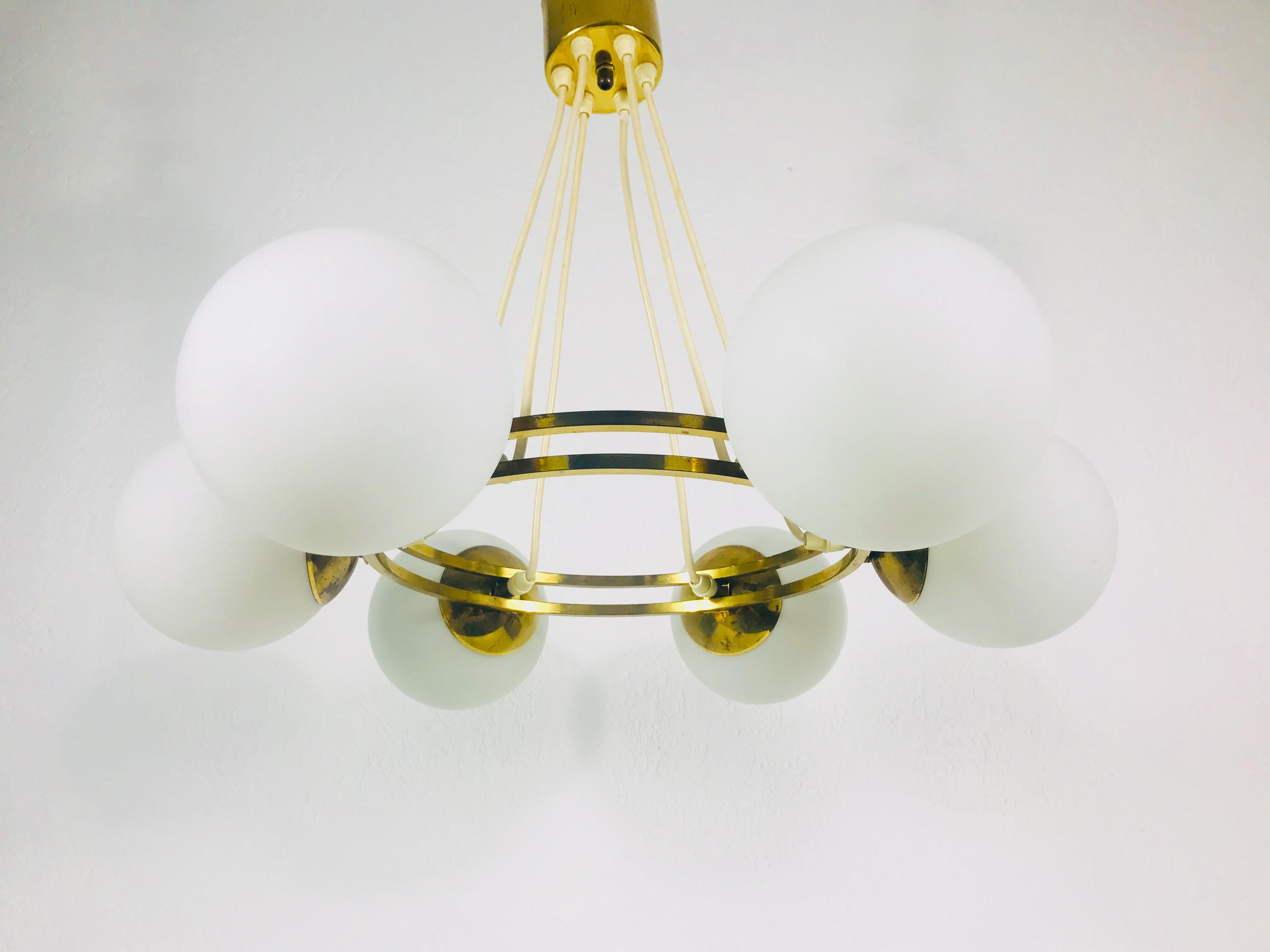 A midcentury Kaiser chandelier made in Germany in the 1960s. It is fascinating with its Space Age design and six opaline glass balls. The circular body of the light is made of polished brass, including the arms. 

Good vintage condition. The light