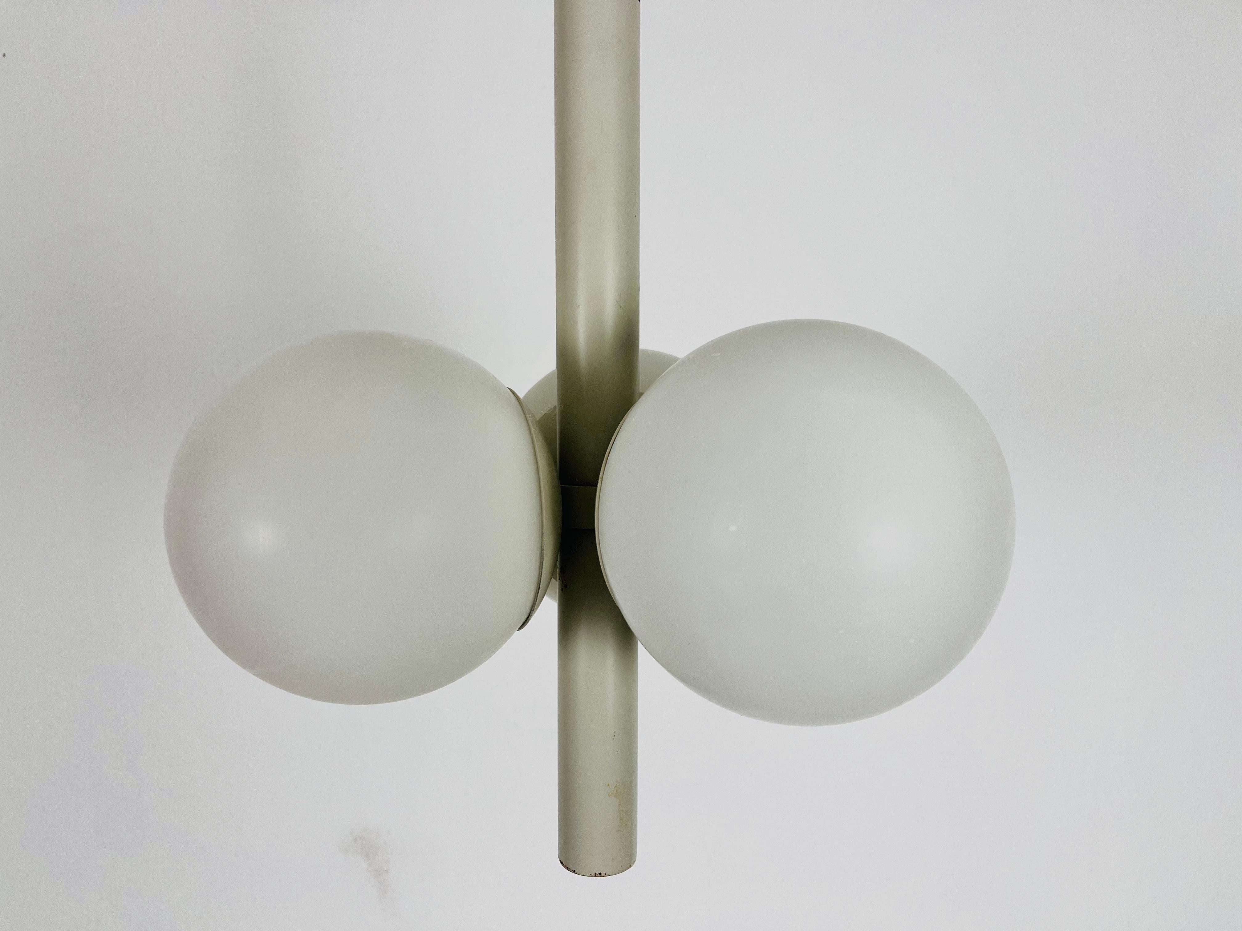 A mid-century Kaiser chandelier made in Germany in the 1960s. It is fascinating with its Space Age design and three opaline glass balls. The body of the light is made of white colored metal.

The light requires three E14 light bulbs. Works with