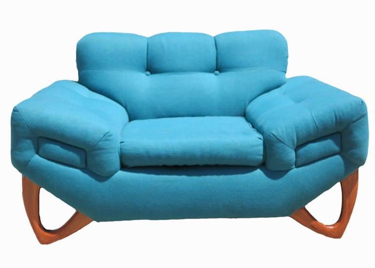 Extra-wide two-seat Gondola lounge chair set in original turquoise fabric and feature a tufted back and angular sloped armrests. The lounge is reminiscent of Adrian Pearsall's distinctive sofa designs, particularly in the use of triangular feet. The