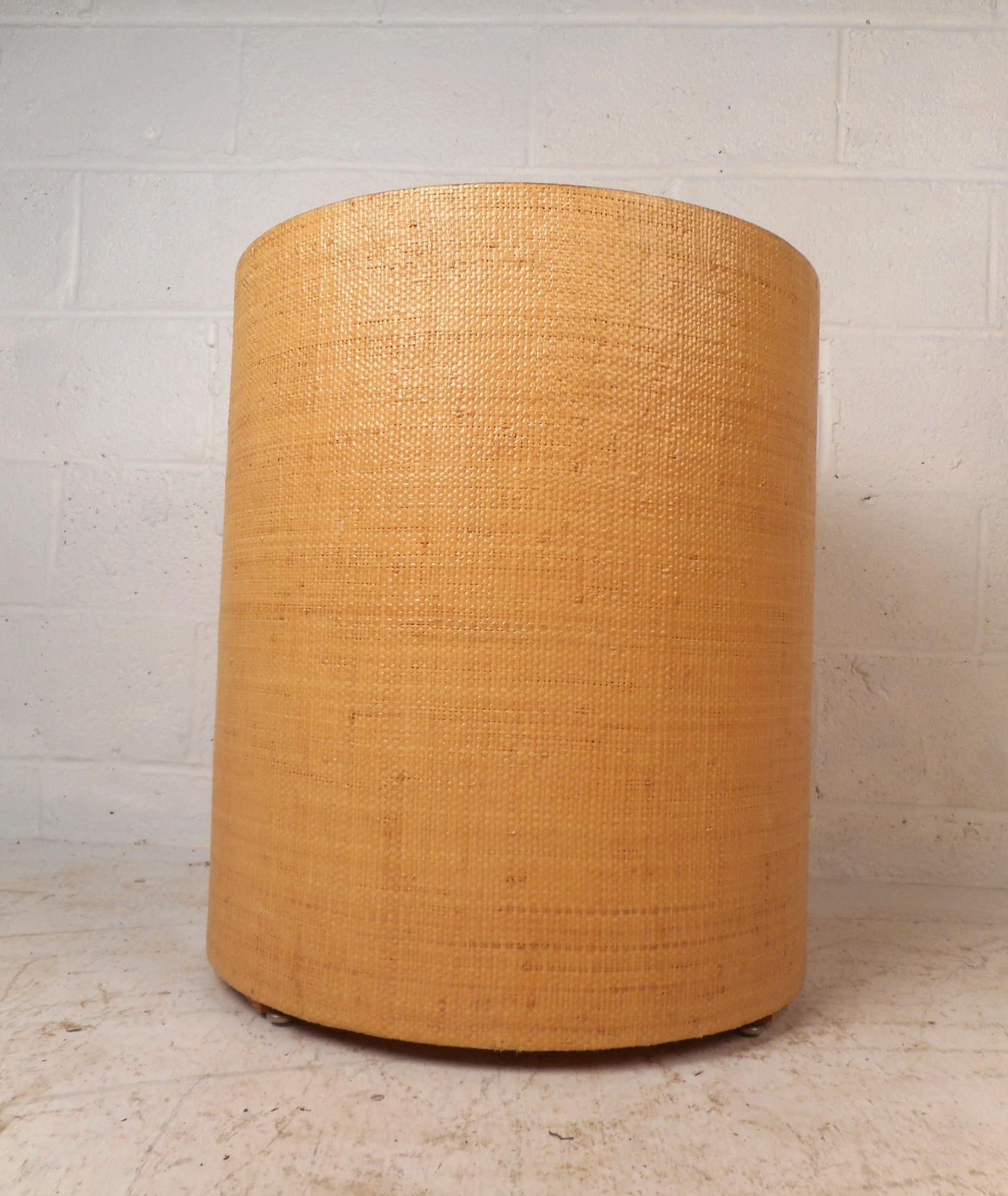 This unique cylindrical side table is enveloped in grasscloth and makes the perfect addition to any setting. The item is versatile and can be used as anything from a side table to a pedestal. It's masterfully crafted and in the style of Karl
