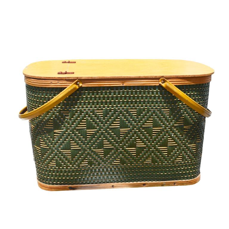 Large hunter green and brown woven picnic basket with handles and a hinged lid. A wonderful way to entertain when dining outdoors! This basket is large and rectangular and topped with a hinged lid that opens to reveal a large compartment for storing