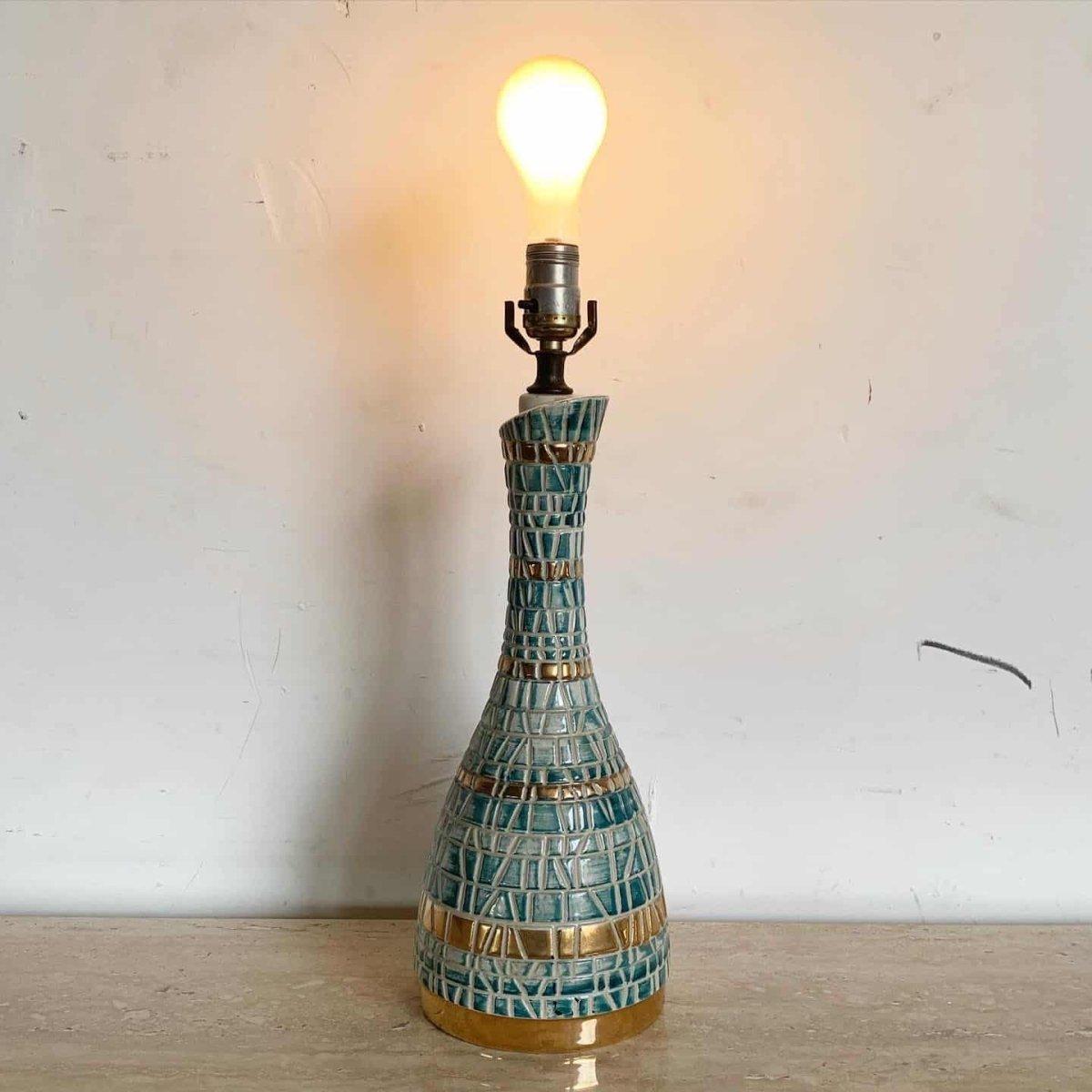 Cette lampe en céramique verte et dorée du milieu du siècle présente un design en fausse mosaïque dans de riches tons émeraude et dorés, offrant un charme vintage avec un éclat sculptural.

Lampe en céramique verte et dorée du milieu du siècle avec