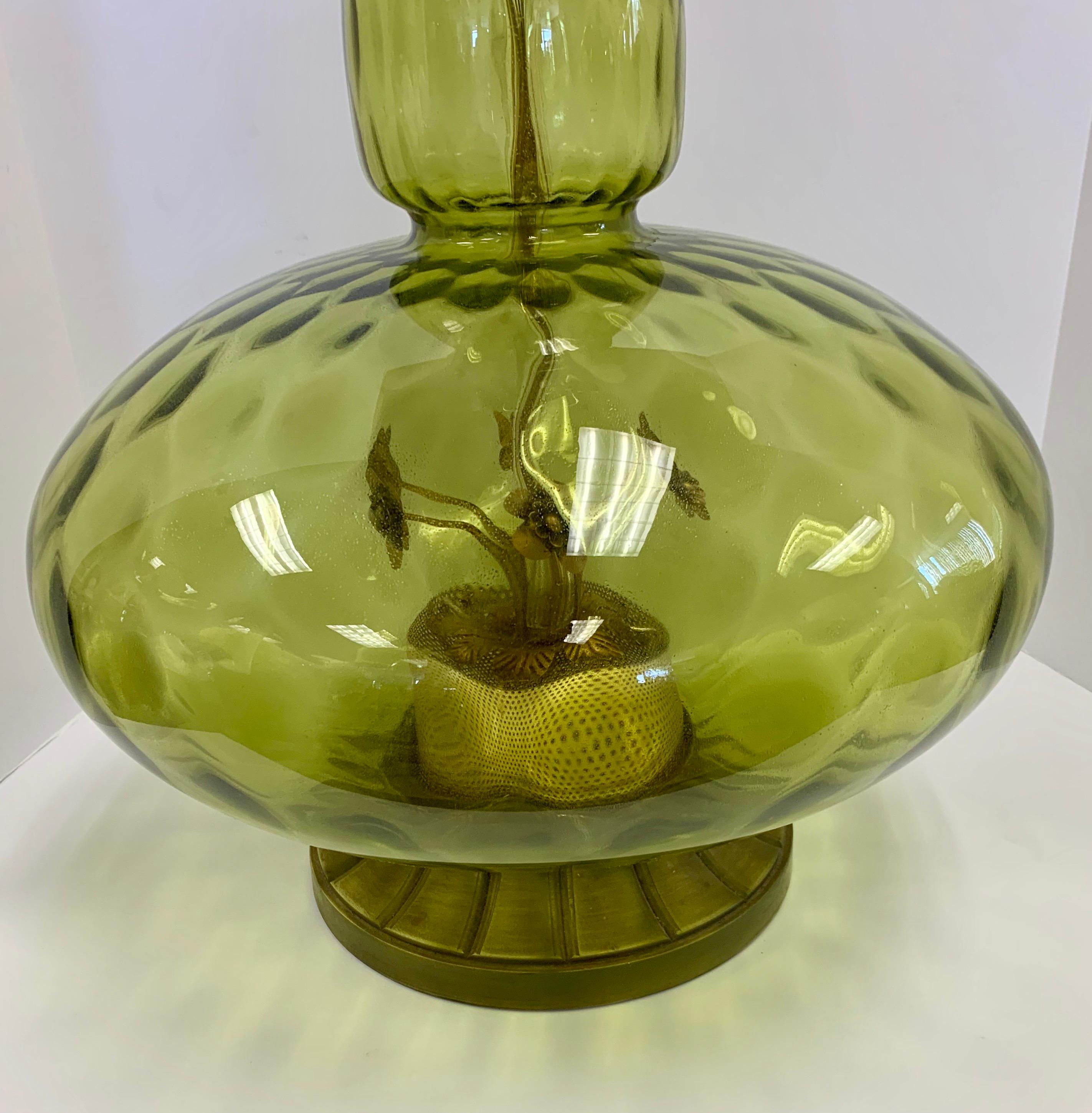 A gorgeous green blown glass large table lamp with floral motif inside glass at base and resin
burning candle sculpture at top. Wired for USA and in perfect working order.