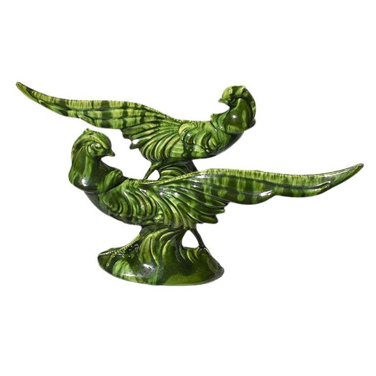 A pair of mcm or regency style ceramic glazed pheasant birds in a beautiful deep green. Each bird features a long outstretched tail and faces toward his back. We would love to see the pair styled on a bookshelf or on a credenza in an entryway. The