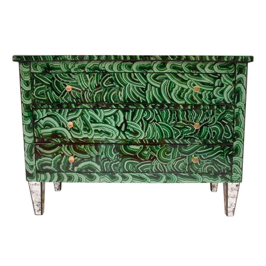 A wonderful Mid-Century Modern style Italian chest of three drawers, made of solid wood structure, covered in green malachite-pattern hand painted glass and brass handles. Feet cladded in colored glass. Drawers inside are in natural wood finish.