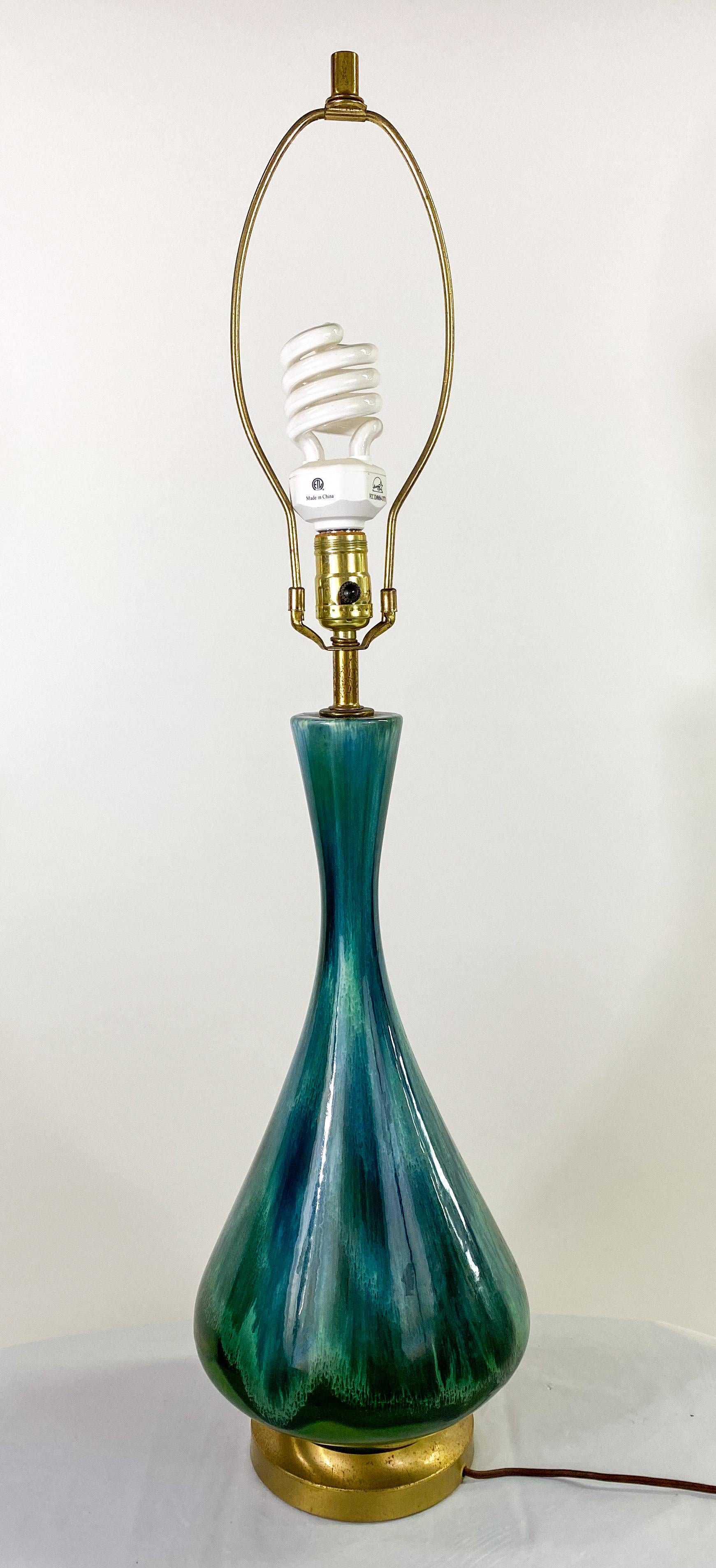 An exquisite Mid-Century Modern table lamp with oversized off-white custom cylindric shaped original shade. The lamp features a malachite inspired green color showing patterns and grains in the style of the beautiful stone. The lamp is shaped like a