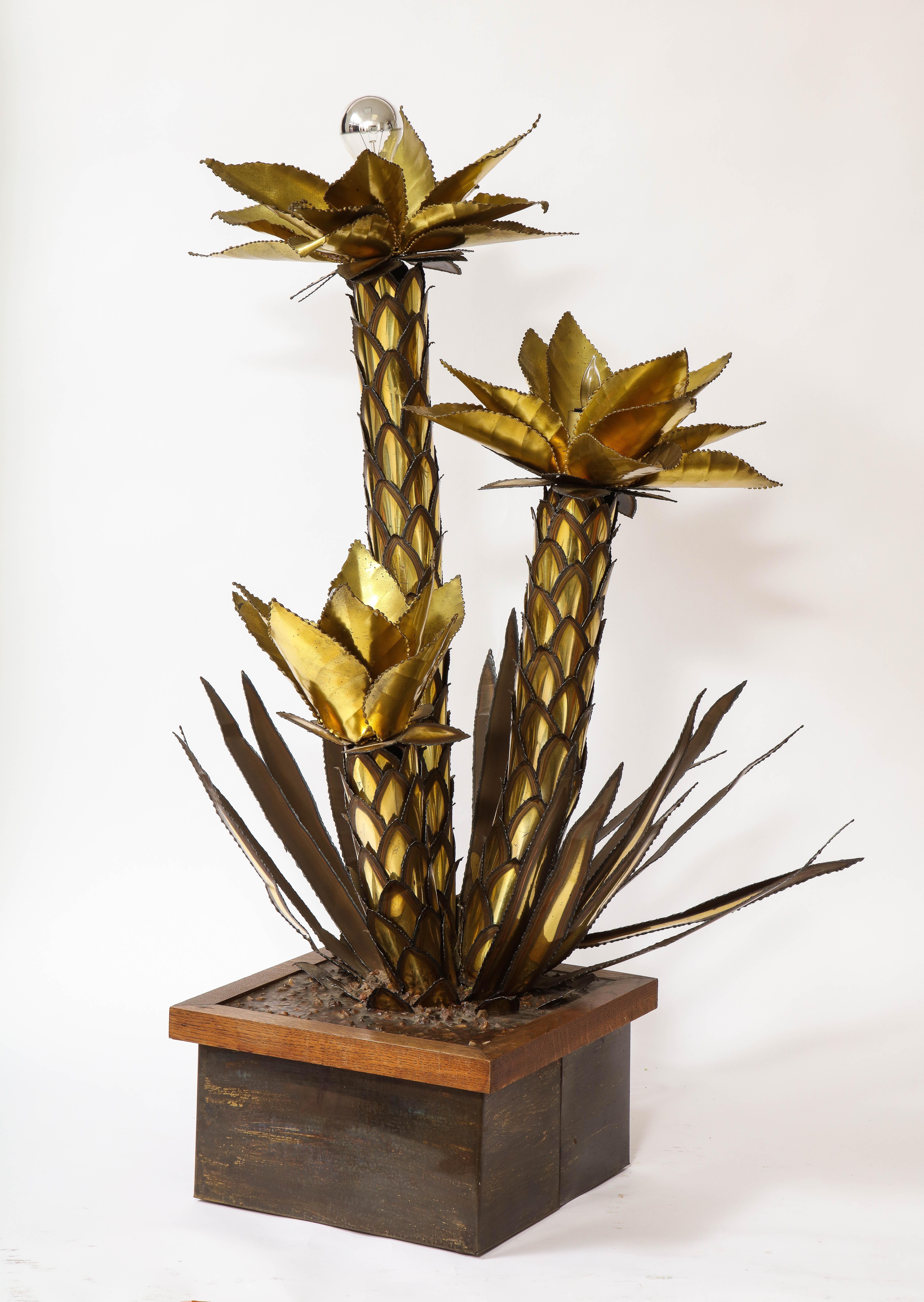 A Mid-Century Modern Group of Patinated and gilt metal palm tree form lamps by Maison Jansen. A large Maison Jansen palm tree table lamp in Hollywood regency style. The gilt and patinated colored leaves of the palm trees reflect a warm atmosphere in