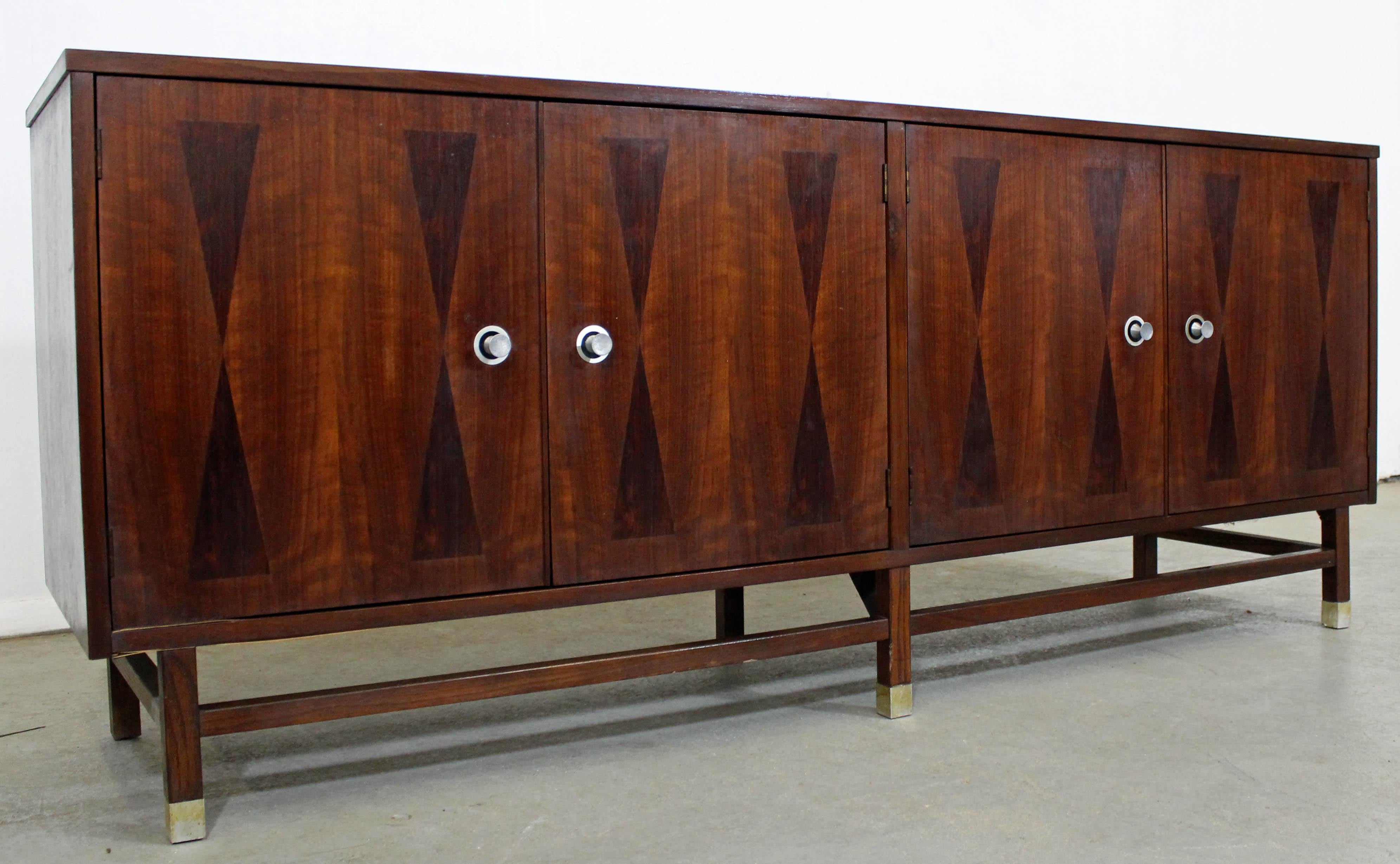 Offered is a beautiful Mid-Century Modern credenza with uniquely parqueted 'bow tie doors'. Features 4 doors with inside shelving on the right and three drawers on the left. It is in excellent condition for its age with refinished tops and sides,