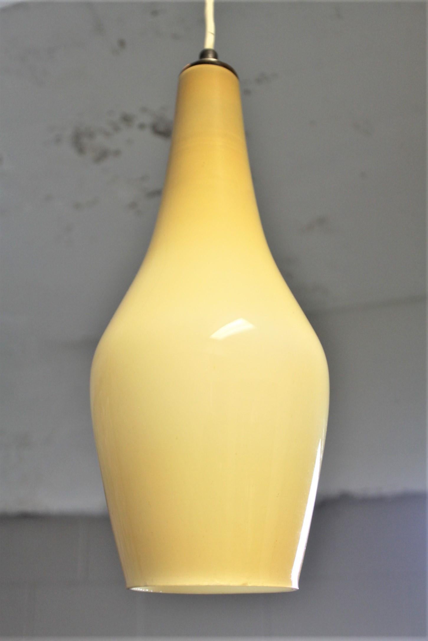 This handcrafted cased glass pendant light fixture is unsigned, but presumed to have been made in Italy or Scandinavia in circa 1965 in the midcentury fog and Morup style. The shade is done in a deep yellow or gold colored glass over white with a