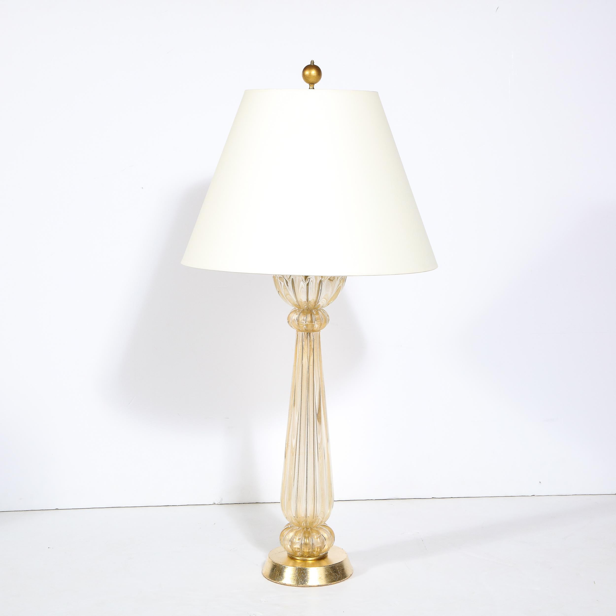 This table lamp is a stunning example of subdued glamor, realized in Murano Italy off the coast of Venice the piece is undeniably decadent and imbued with the highest quality craftsmanship. 24K Gold flecks are dispersed throughout the transparent