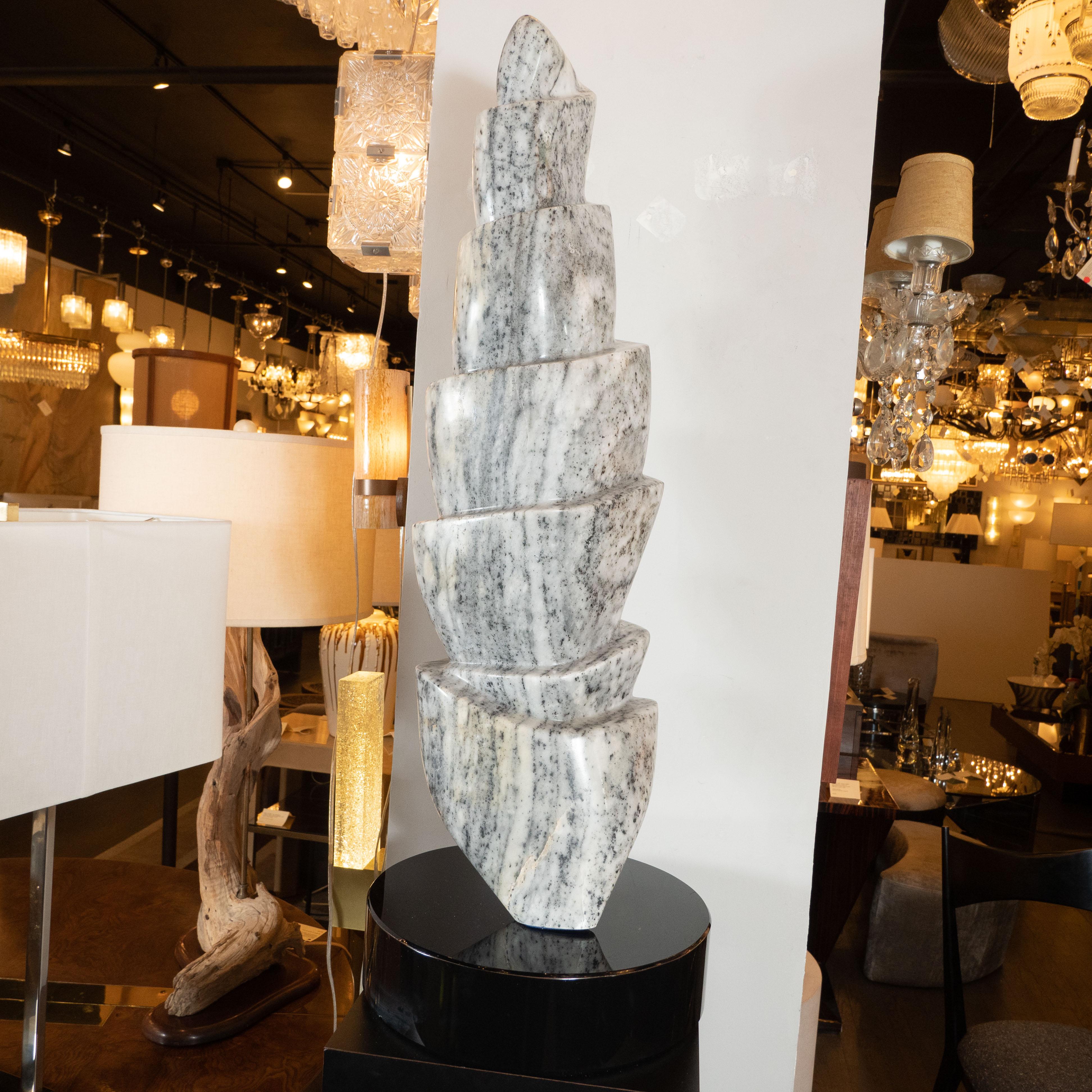 This dynamic and refined Mid-Century Modern sculpture was realized in the United States, circa 1970. It features a TOTEM hand carved form consisting of various tiers of grisaille granite- replete with a rich and organic innate texture. The granite