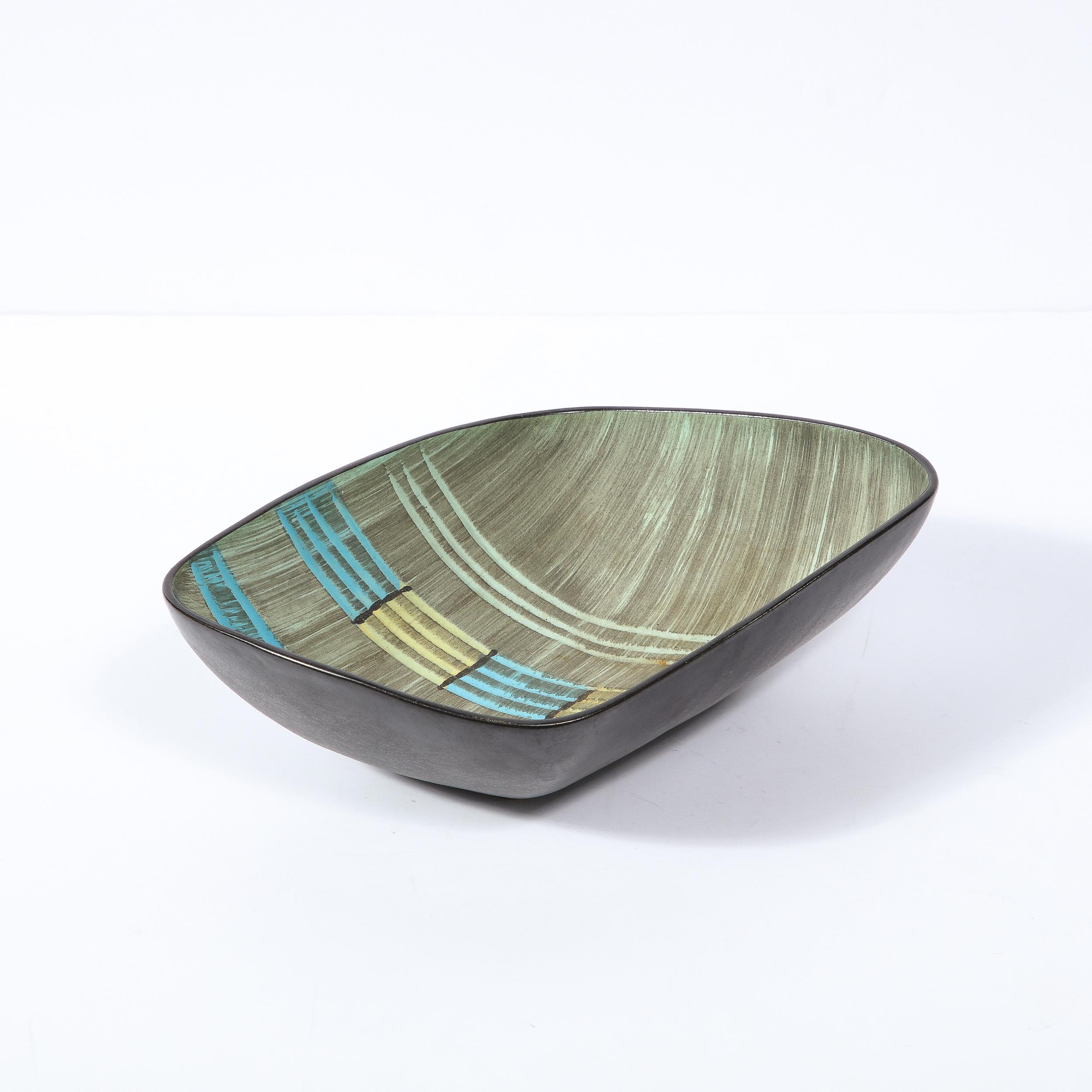 This sophisticated Mid-Century Modern ceramic bowl was realized in Germany circa 1950. It features a rectangular form with raised sides and a concave center with a black exterior and a finely striated gunmetal interior. Geometric banded lines in