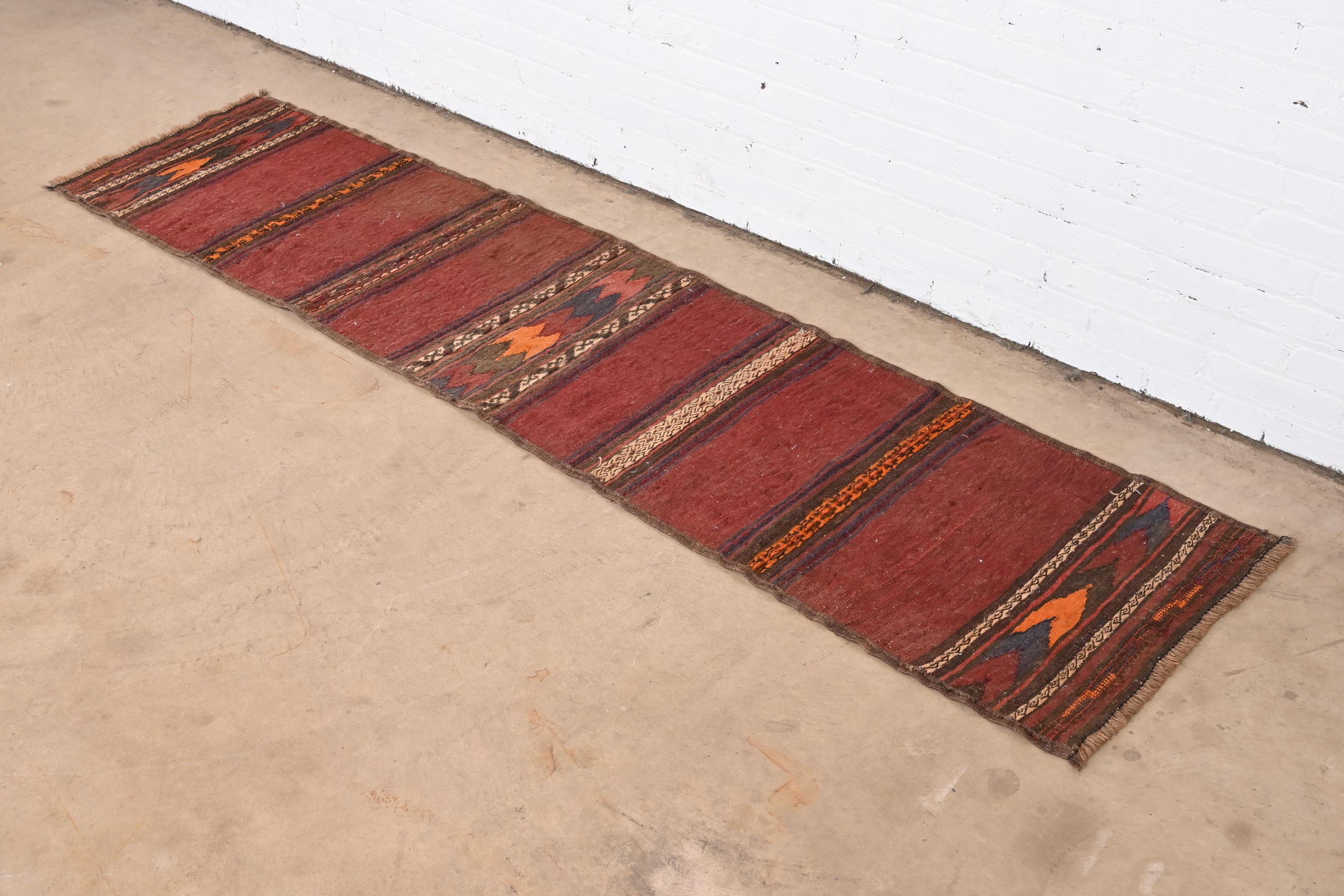 A gorgeous Mid-Century Modern hand-woven Afghan kilim flat weave runner rug

Mid-20th Century

Beautiful geometric design, with predominant colors in maroon, orange, blue, and brown.

Measures: 23