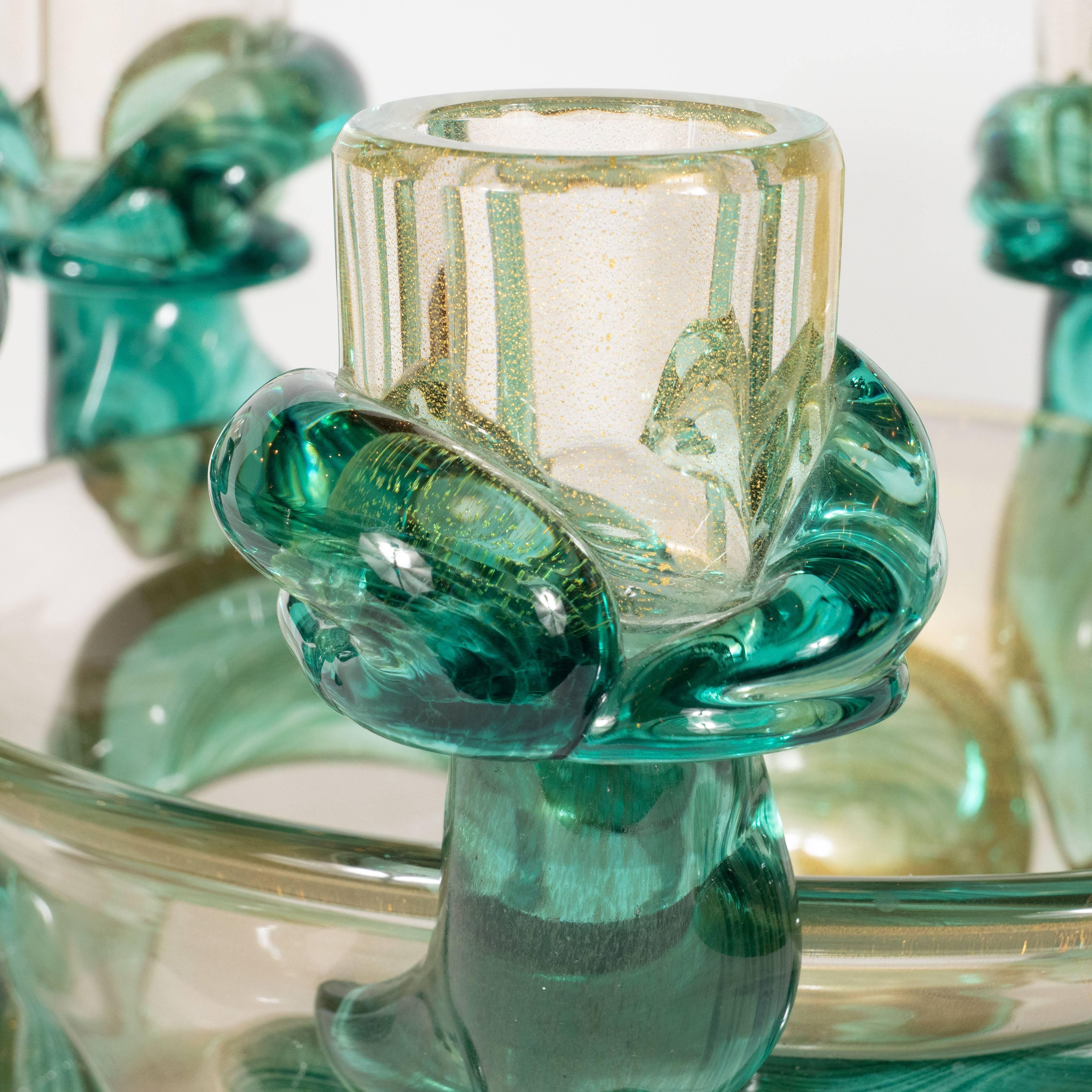 This stunning Mid-Century Modern sculptural handblown glass centerpiece bowl was realized in Murano, Italy- the islands off the coast of Venice- by the esteemed maker Seguso, circa 1960. The center bowl and candleholders are composed of translucent