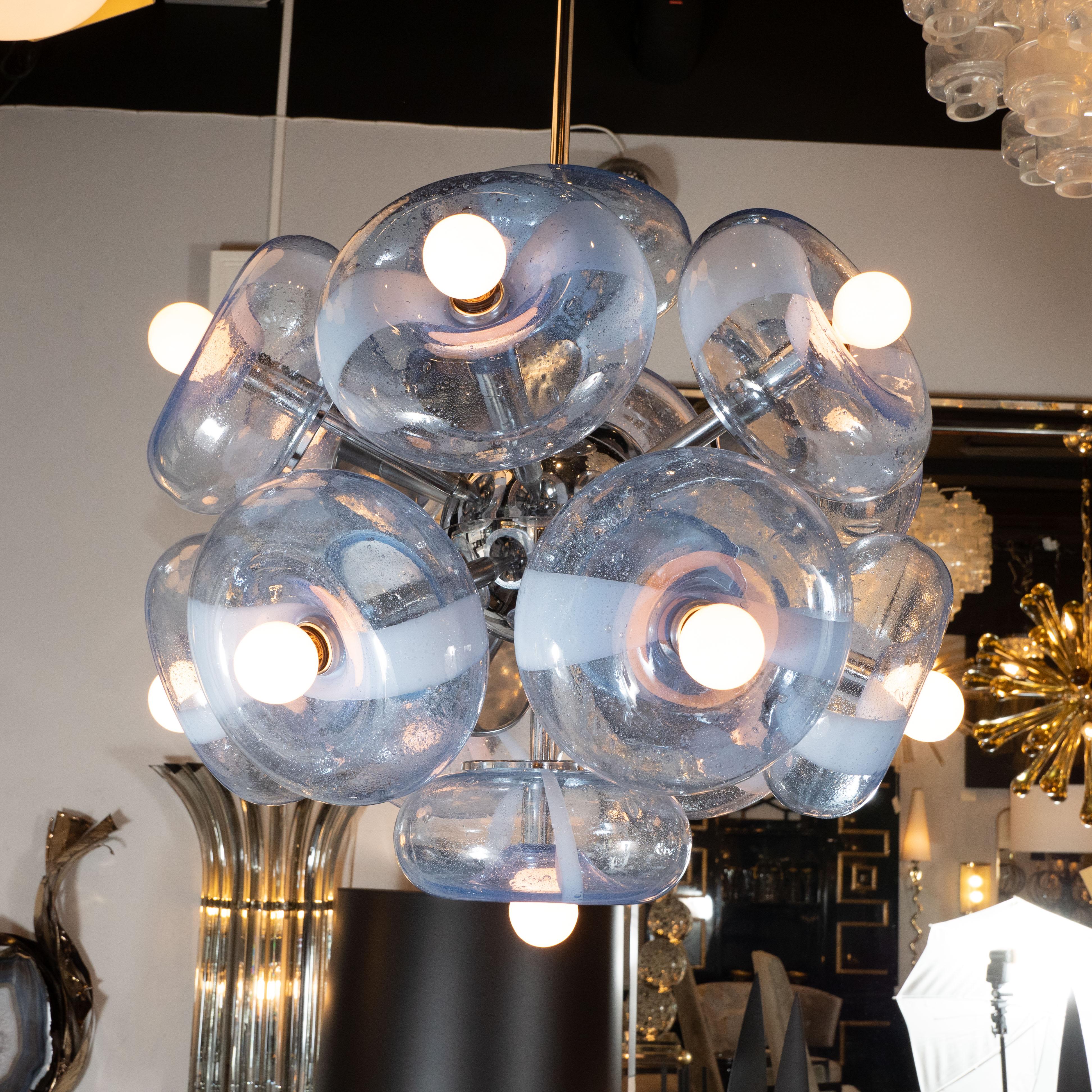 This stunning and graphic sputnik was realized in Italy, circa 1950. It features twelve torus shaped shades in hand blown Murano glass of a beautiful periwinkle shade- replete with an abundance of miniscule bubbles embedded within, suggesting