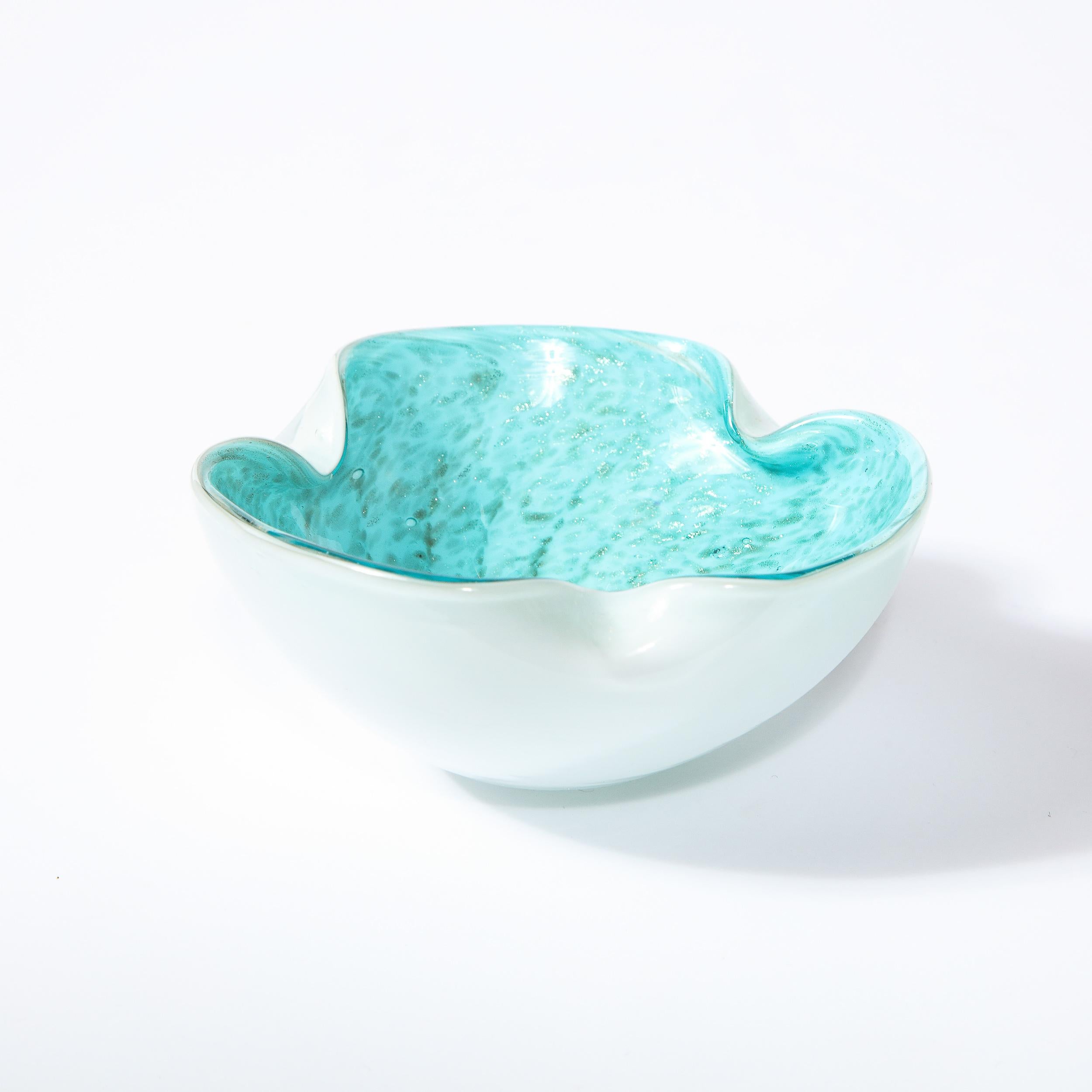 This stunning Mid-Century Modern bowl was realized in Murano, Italy- the island off the coast of Venice renowned for centuries for its superlative glass production. It features a circular form with raised sides and scallooped detailing. The bowl has