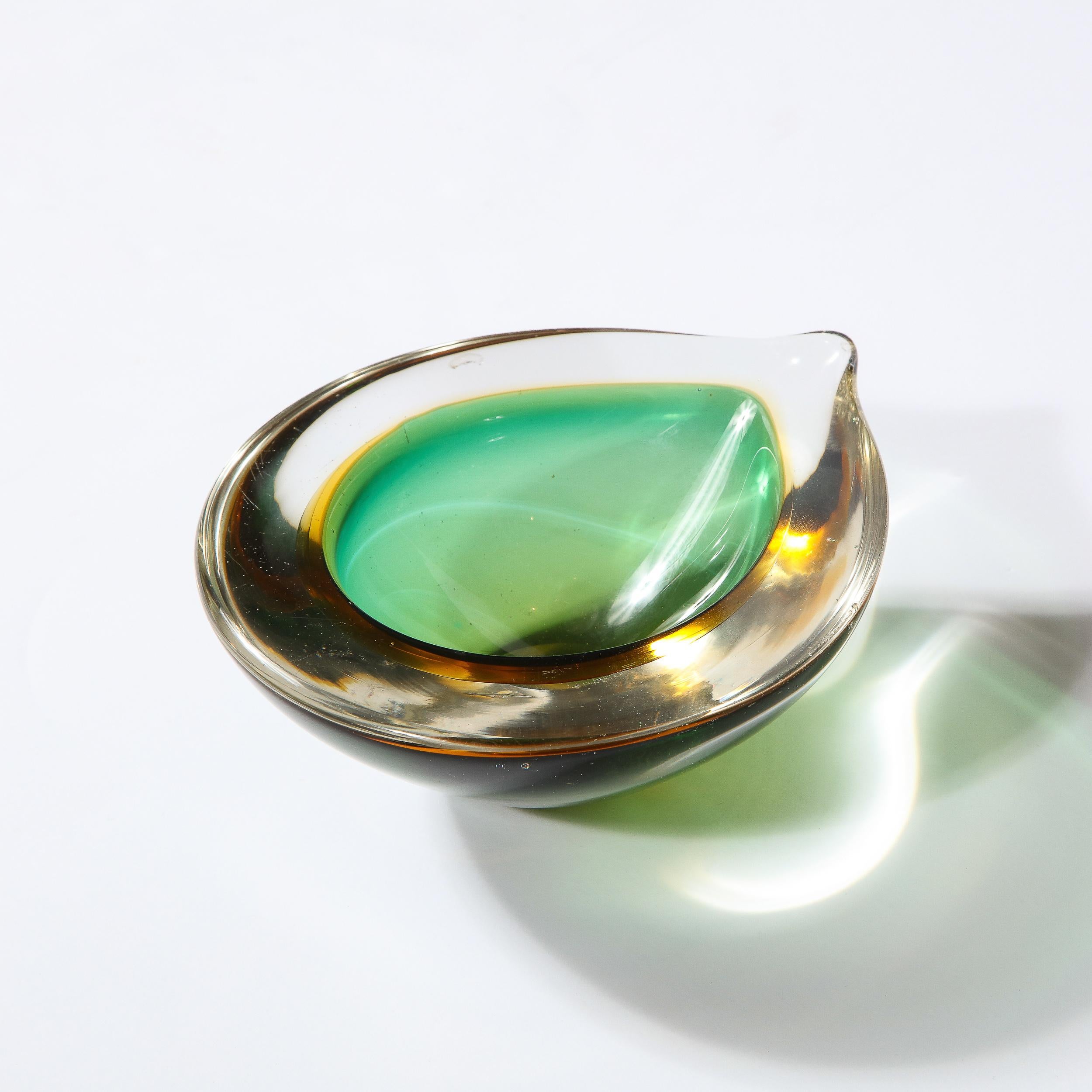 This stunning Mid-Century Modern bowl was realized in Murano, Italy- the island off the coast of Venice renowned for centuries for its superlative glass production. It features an ovoid teardrop form with an emerald interior and a translucent